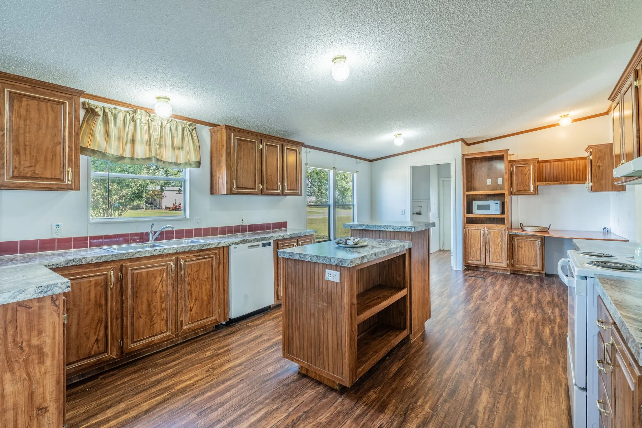 Kitchen: Spacious kitchen featuring wood cabinetry, a center island, ample counter space, and wood-look flooring.