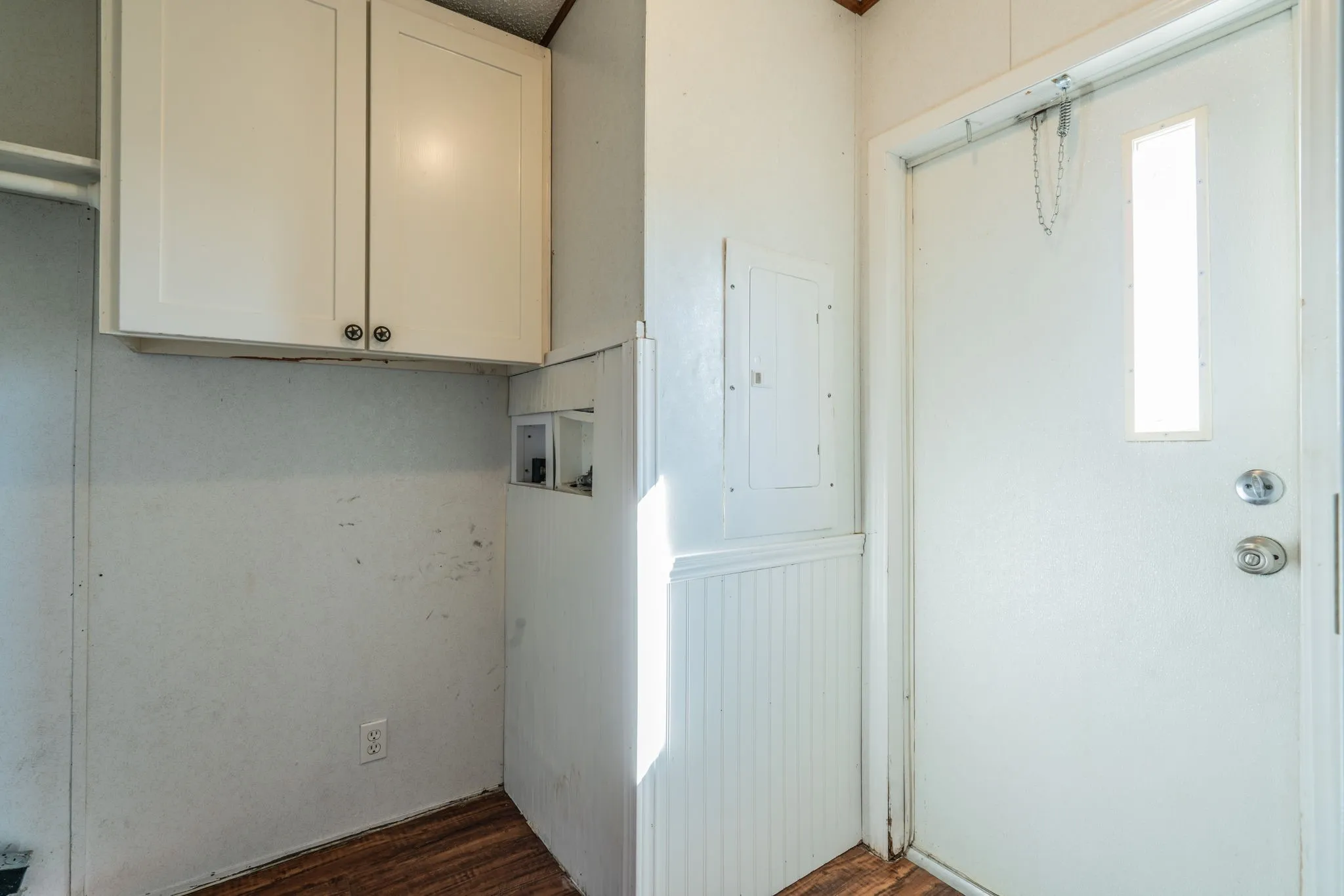 Utility Room: Dedicated utility area featuring overhead storage cabinets, wood-look flooring, and a nearby exterior access door.
Copy All 8 Captions