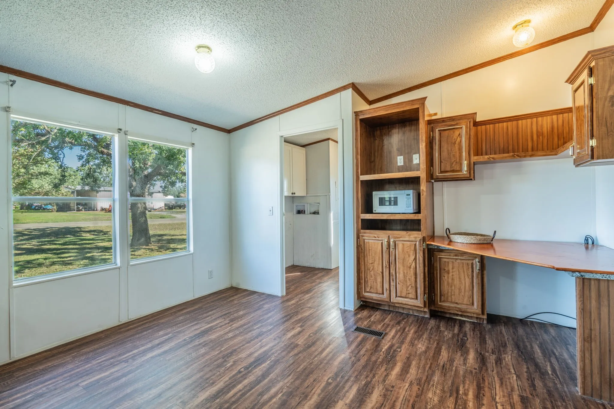 Dining Area: Sunlit dining space with large windows, wood-look flooring, built-in cabinetry, and a convenient counter area.