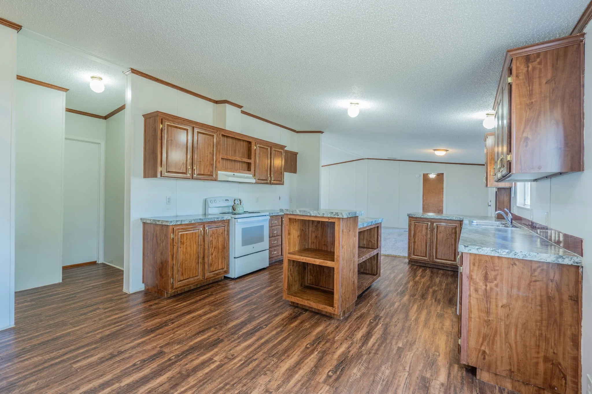 Kitchen: Wide-angle view highlighting the kitchen's functional layout, generous cabinetry, and connection to the adjoining living space.