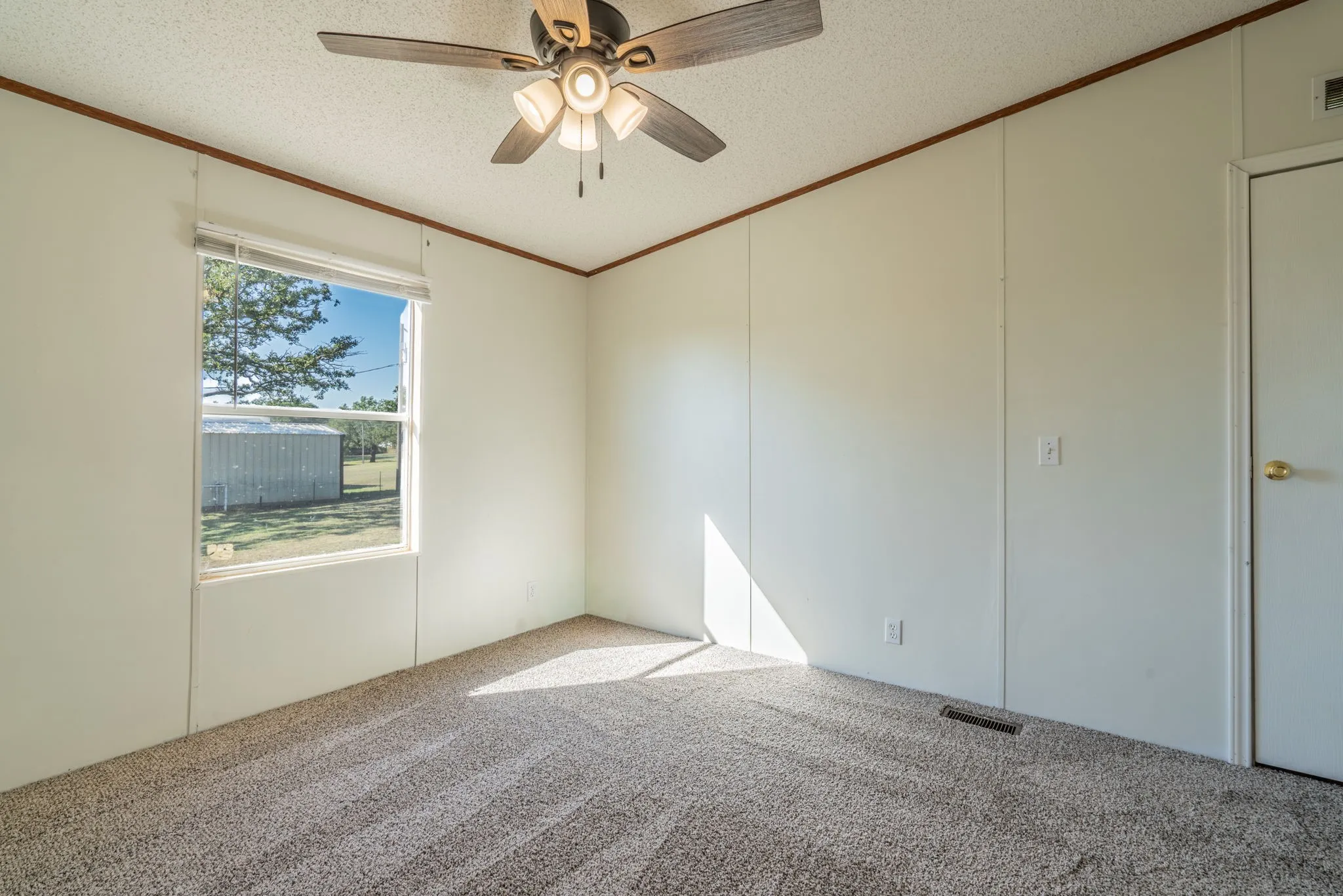 Bedroom: Alternate view showcasing the carpeted floor, ceiling fan, closet door, and window overlooking the yard.