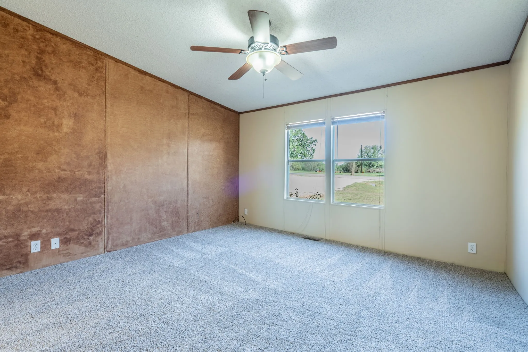 Bedroom: Carpeted bedroom featuring a textured accent wall, ceiling fan with light, and two windows.