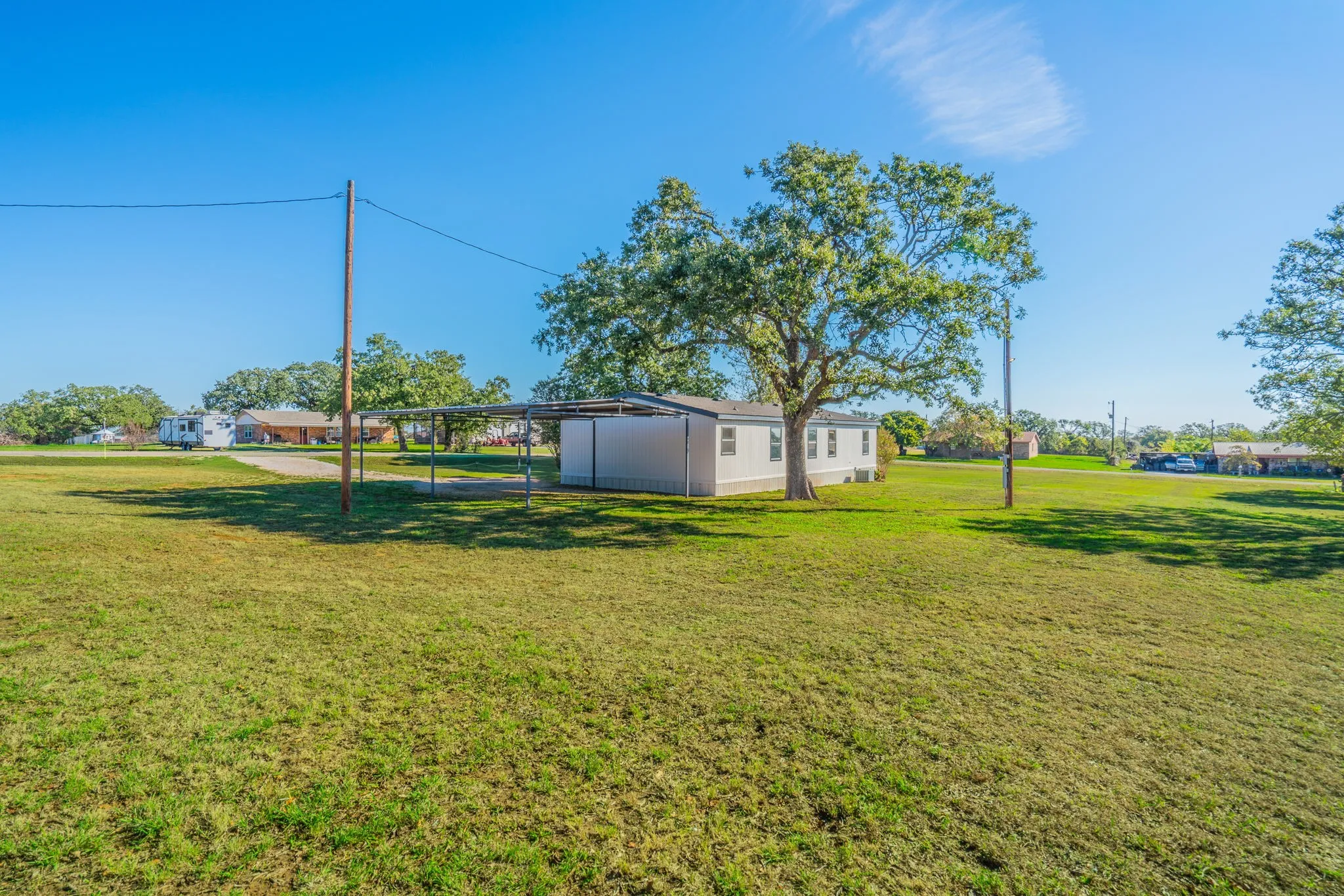 Rear Exterior: Wide-angle view highlighting the home's exterior, covered parking structure, and mature trees across the grounds.