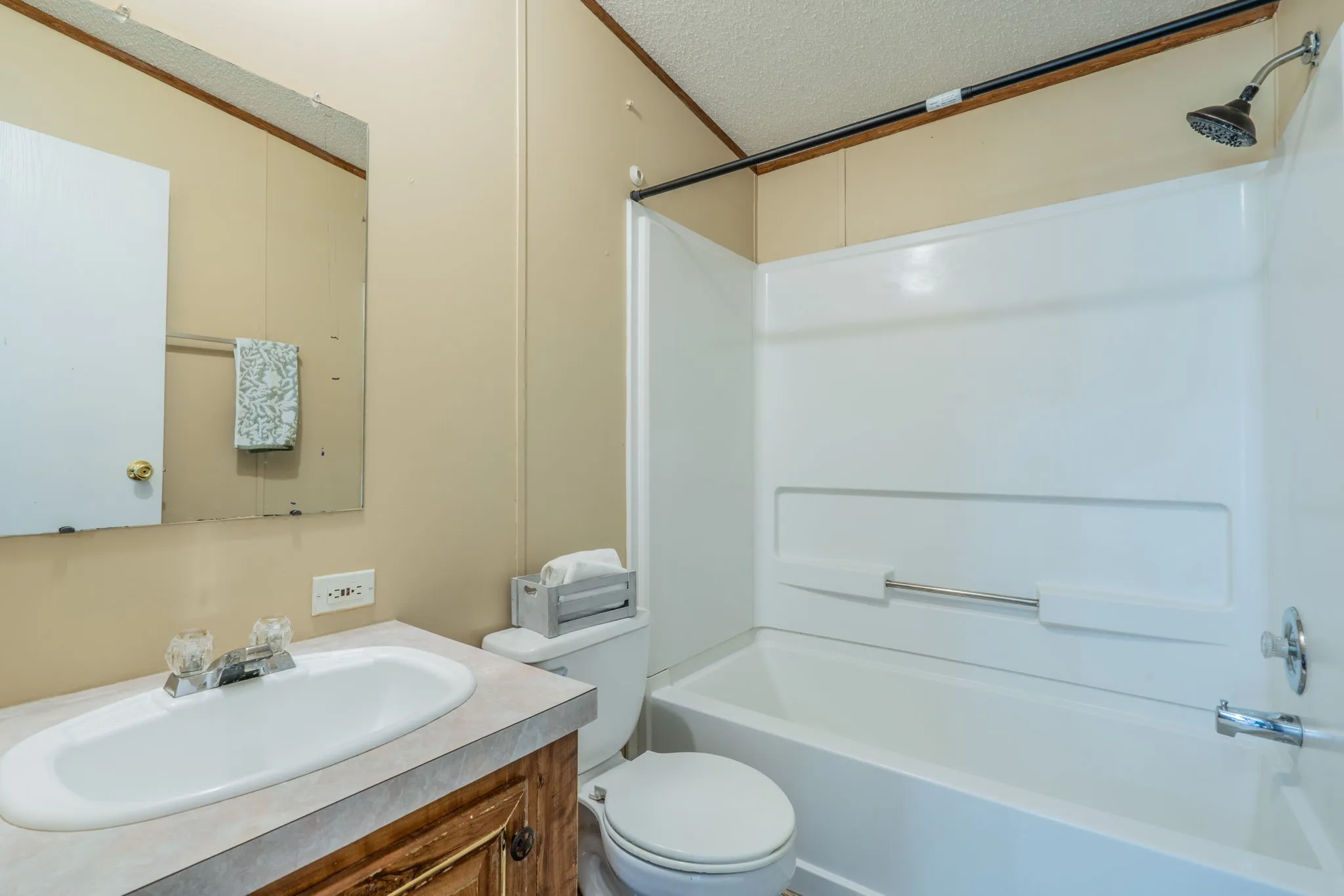 Secondary Bathroom: Full bathroom featuring a tub and shower combination, single-sink vanity, wood cabinetry, and wall-mounted mirror.