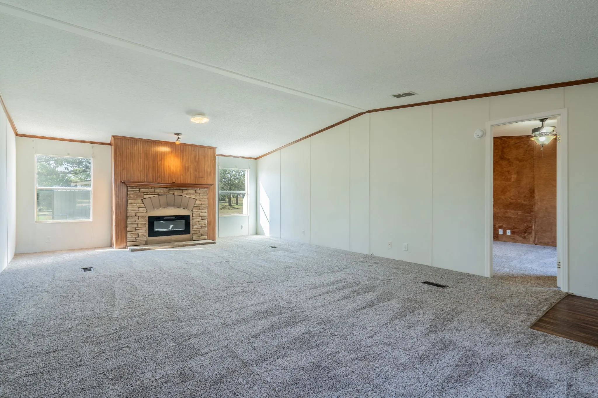 Living Room: Stone-accented fireplace with wood-paneled surround creates a focal point between two windows.