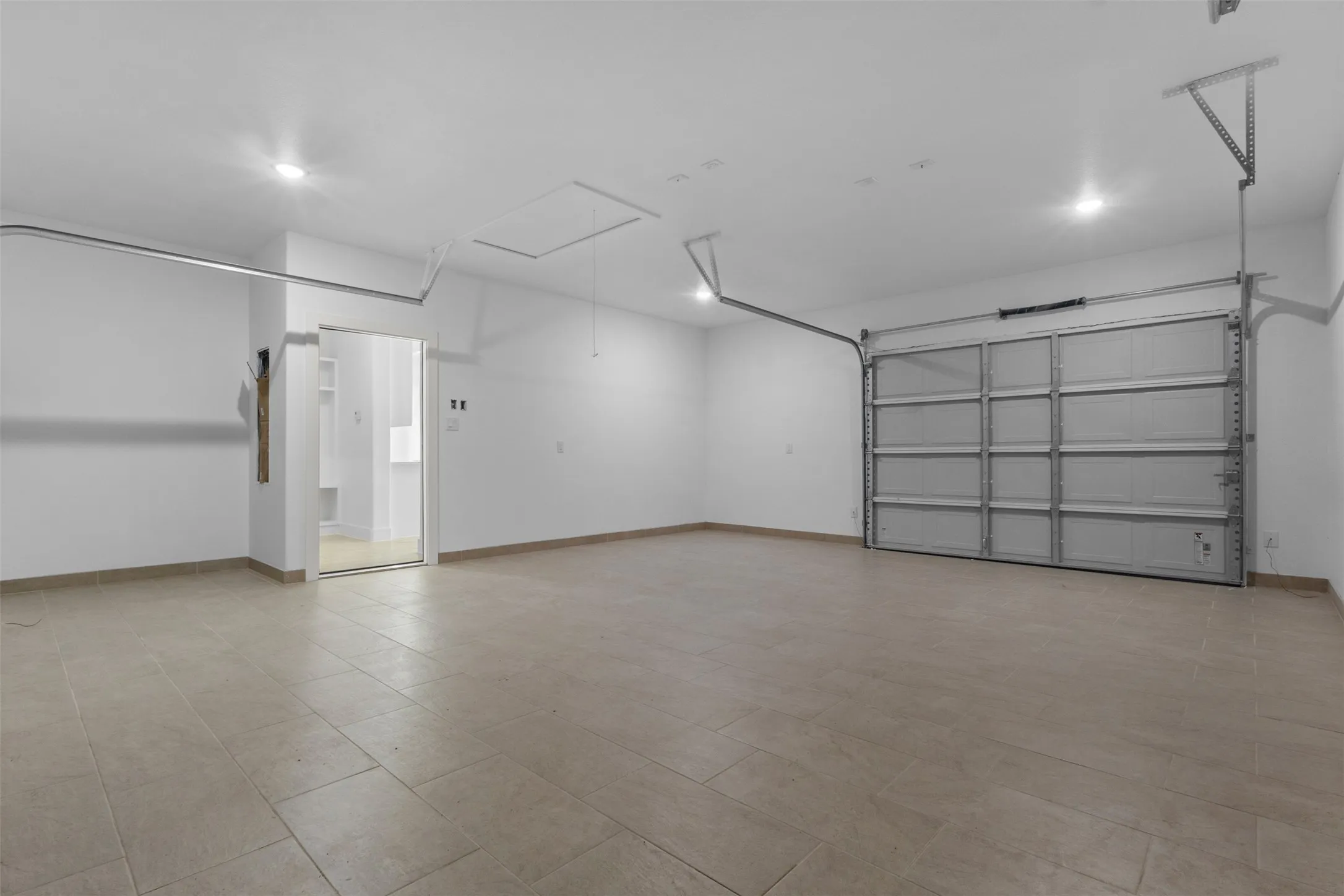 Spacious garage with tile flooring, recessed lighting, and a roll-up garage door