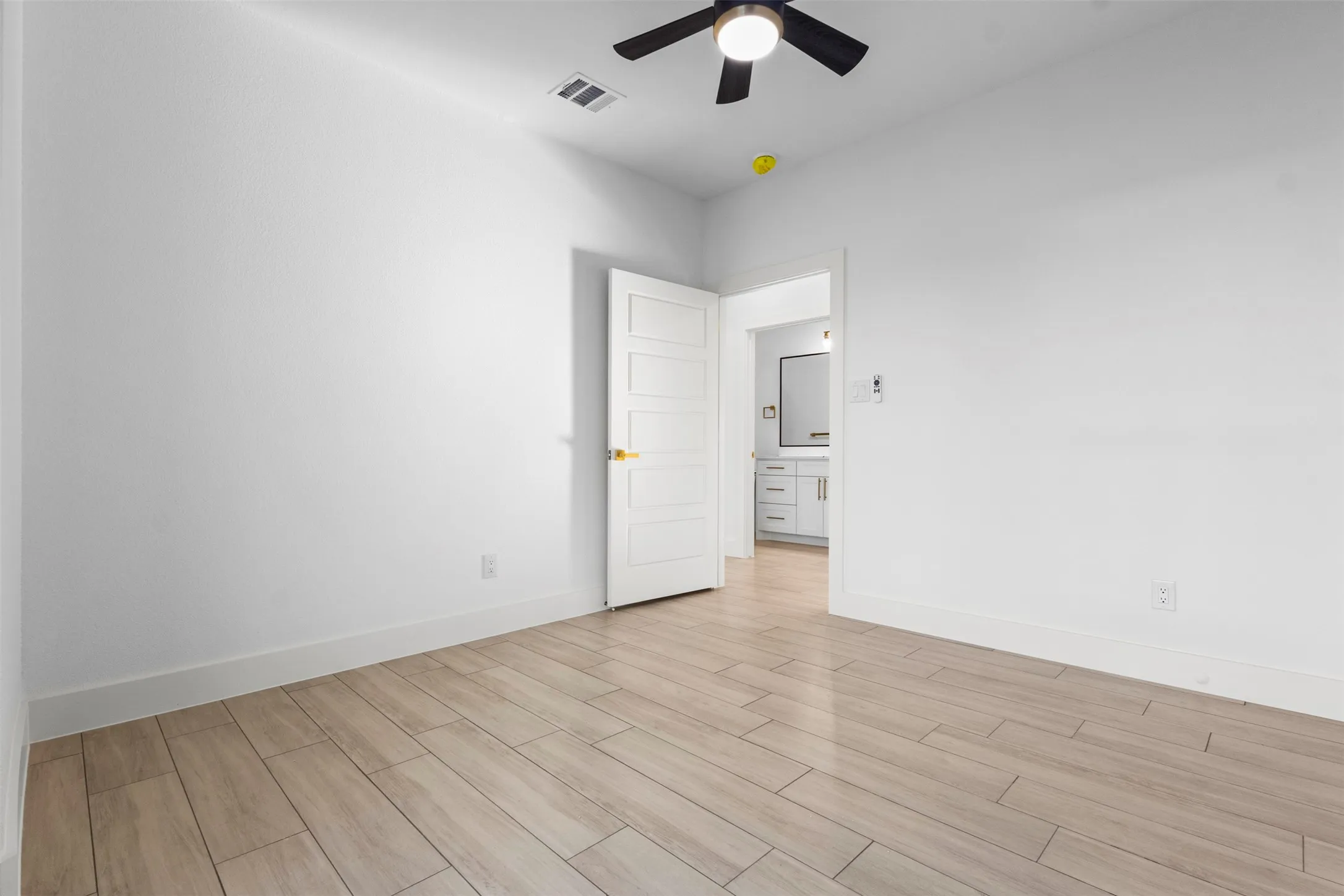 Wood-finish flooring, contemporary ceiling fan, and white five-panel interior door
