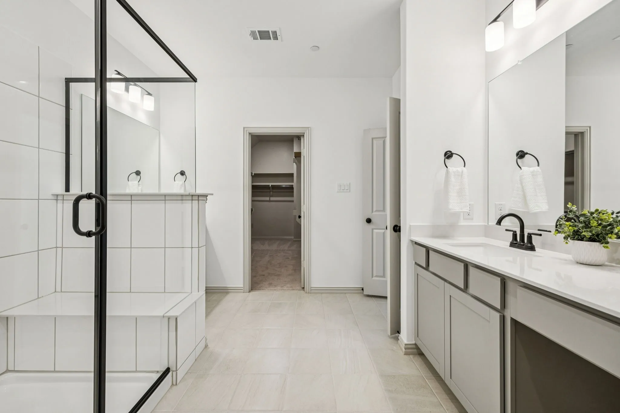 Enclosed shower with a built-in bench, dual vanity with a white countertop, and contemporary black fixtures