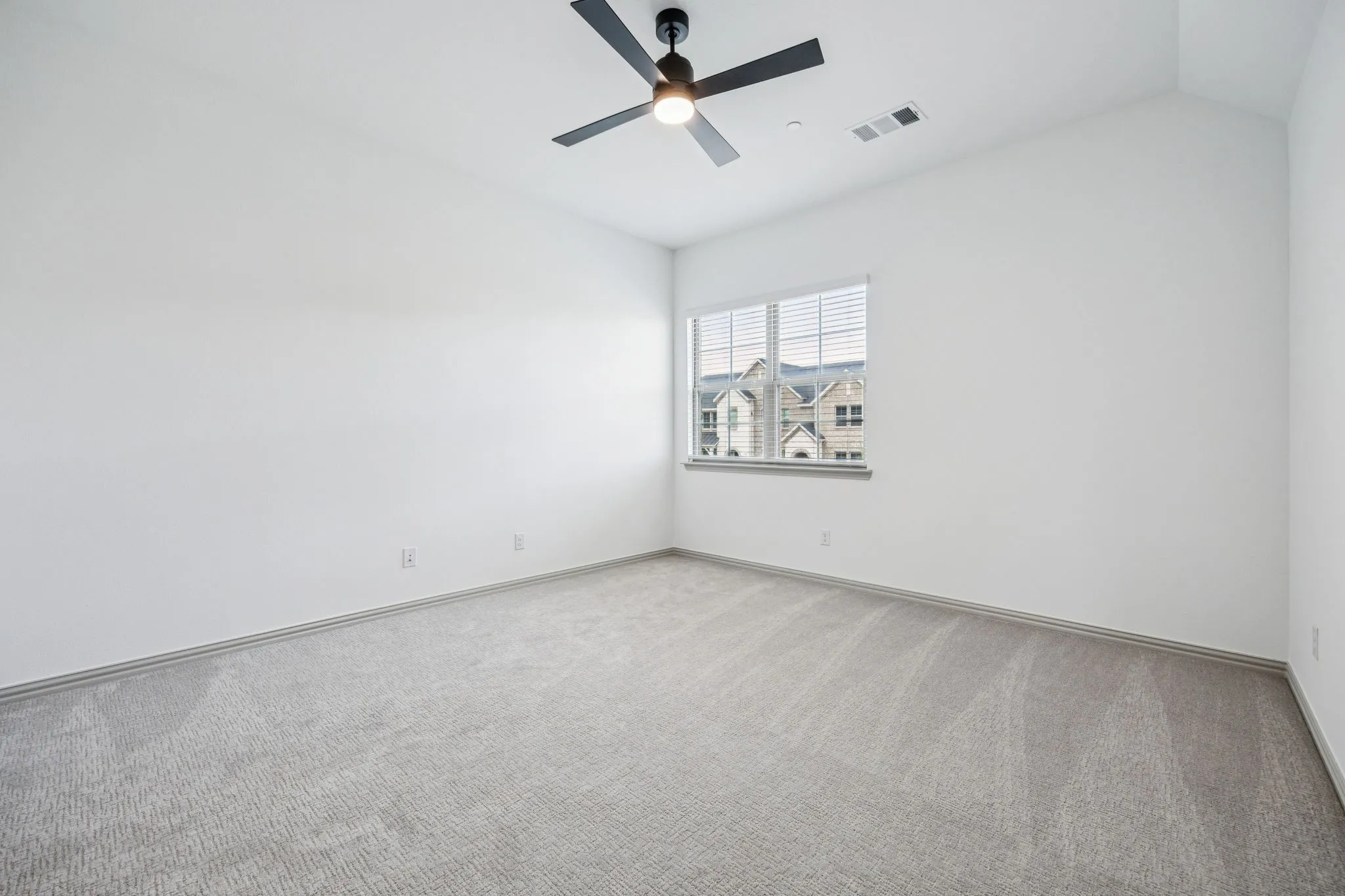 Vaulted ceiling with a black ceiling fan, light gray carpet, and a window with blinds