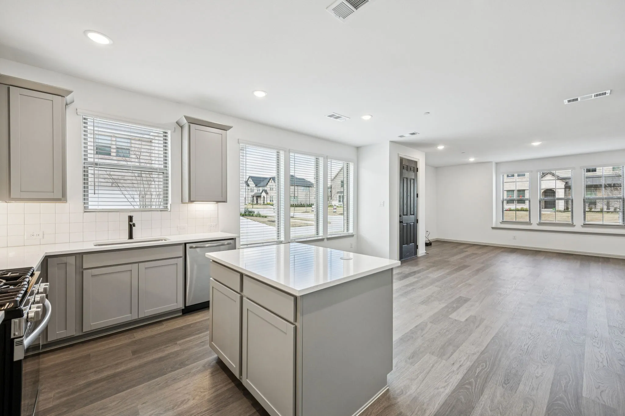 Open-concept kitchen and living area featuring wood-finish flooring, recessed lighting, and a kitchen island with a light-toned countertop