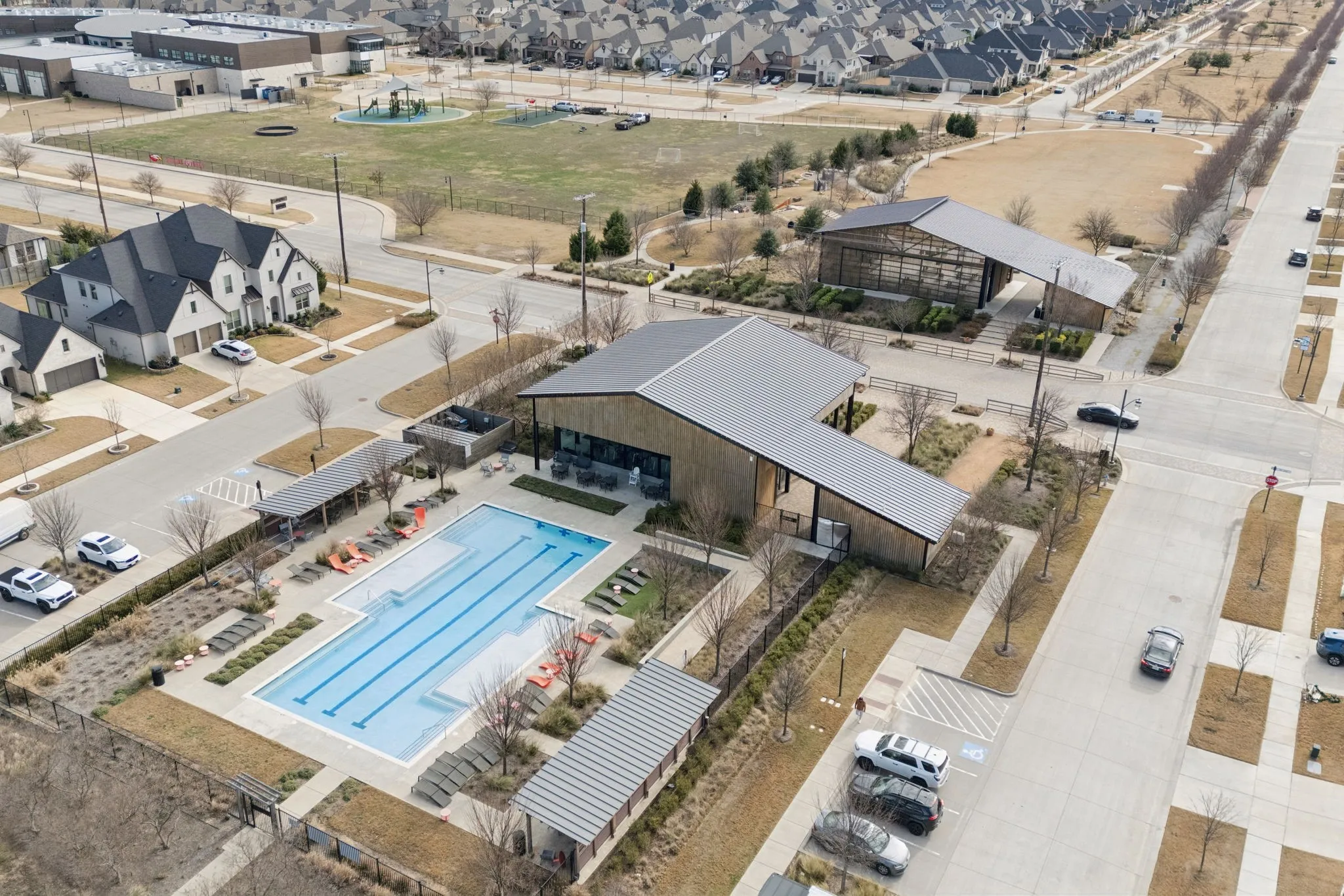 Community pool with lap lanes, surrounding lounge areas, modern amenity buildings, and dedicated parking