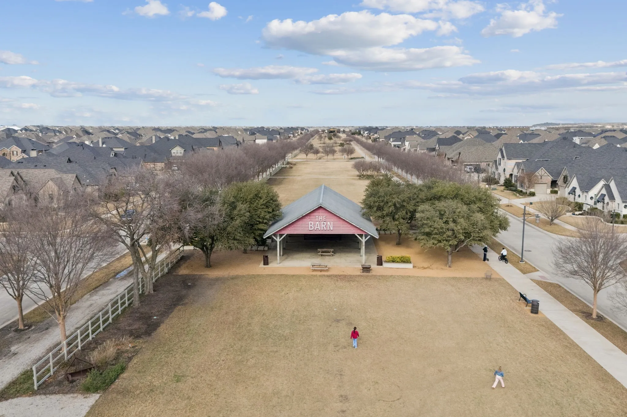 Expansive green space with a red-roofed pavilion, surrounded by residential properties and mature trees