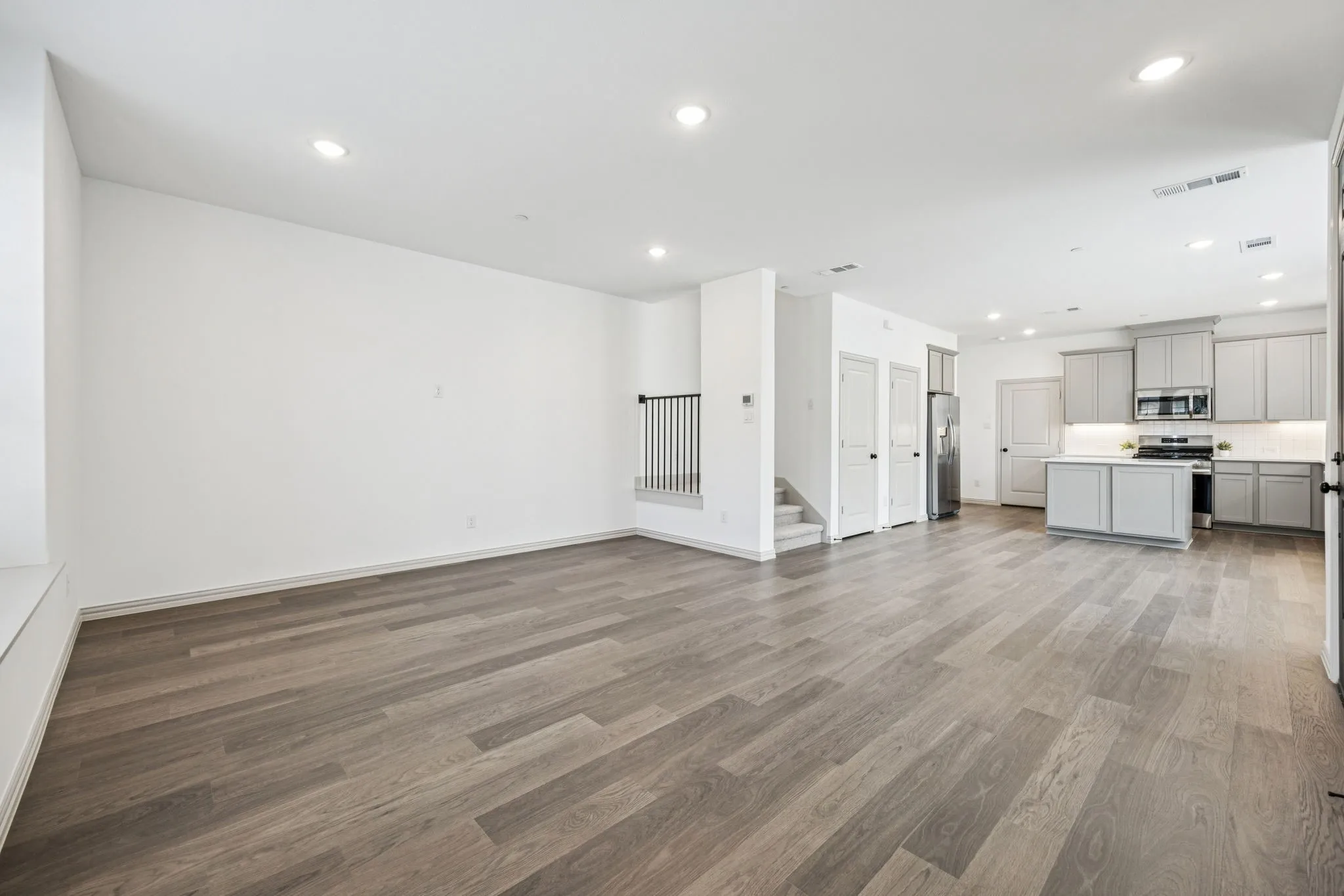 Recessed lighting illuminates wood-finish flooring throughout
