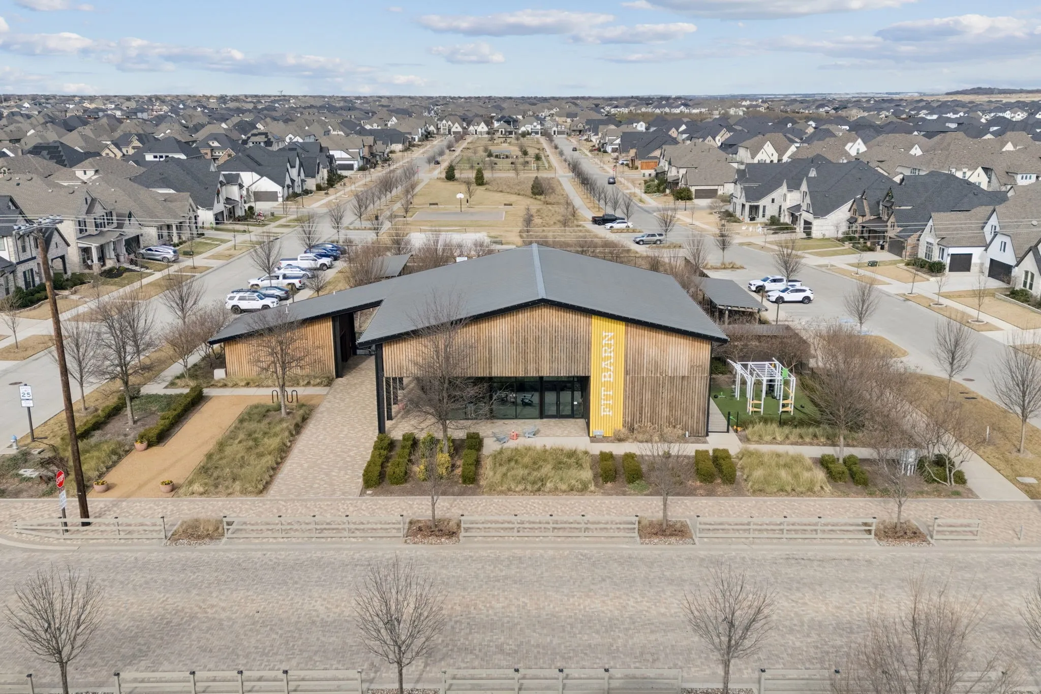 Community building with a dark gray roof, wood-finish siding, and a paved entrance