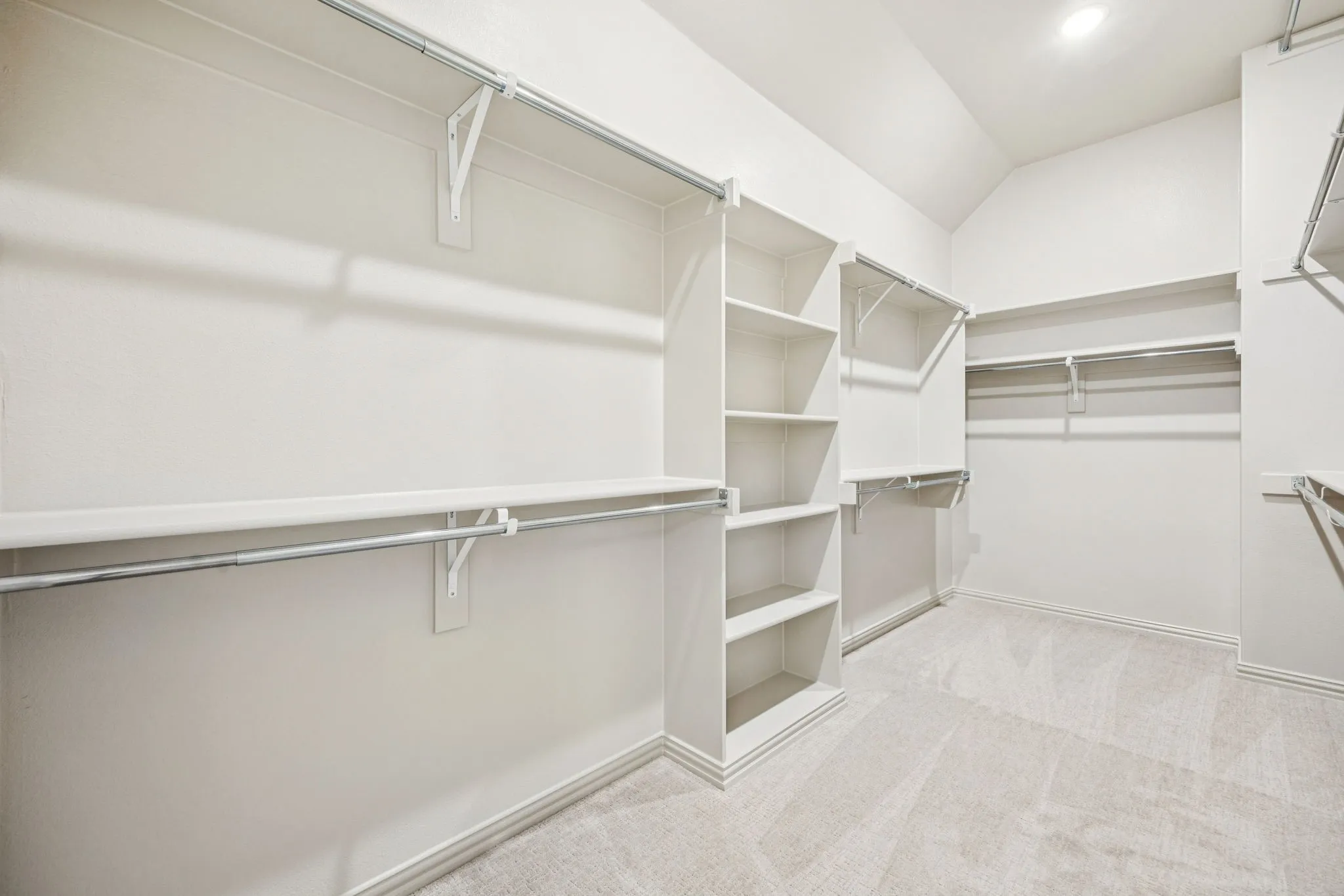 Custom closet system with multiple shelving units, hanging rods, and recessed lighting