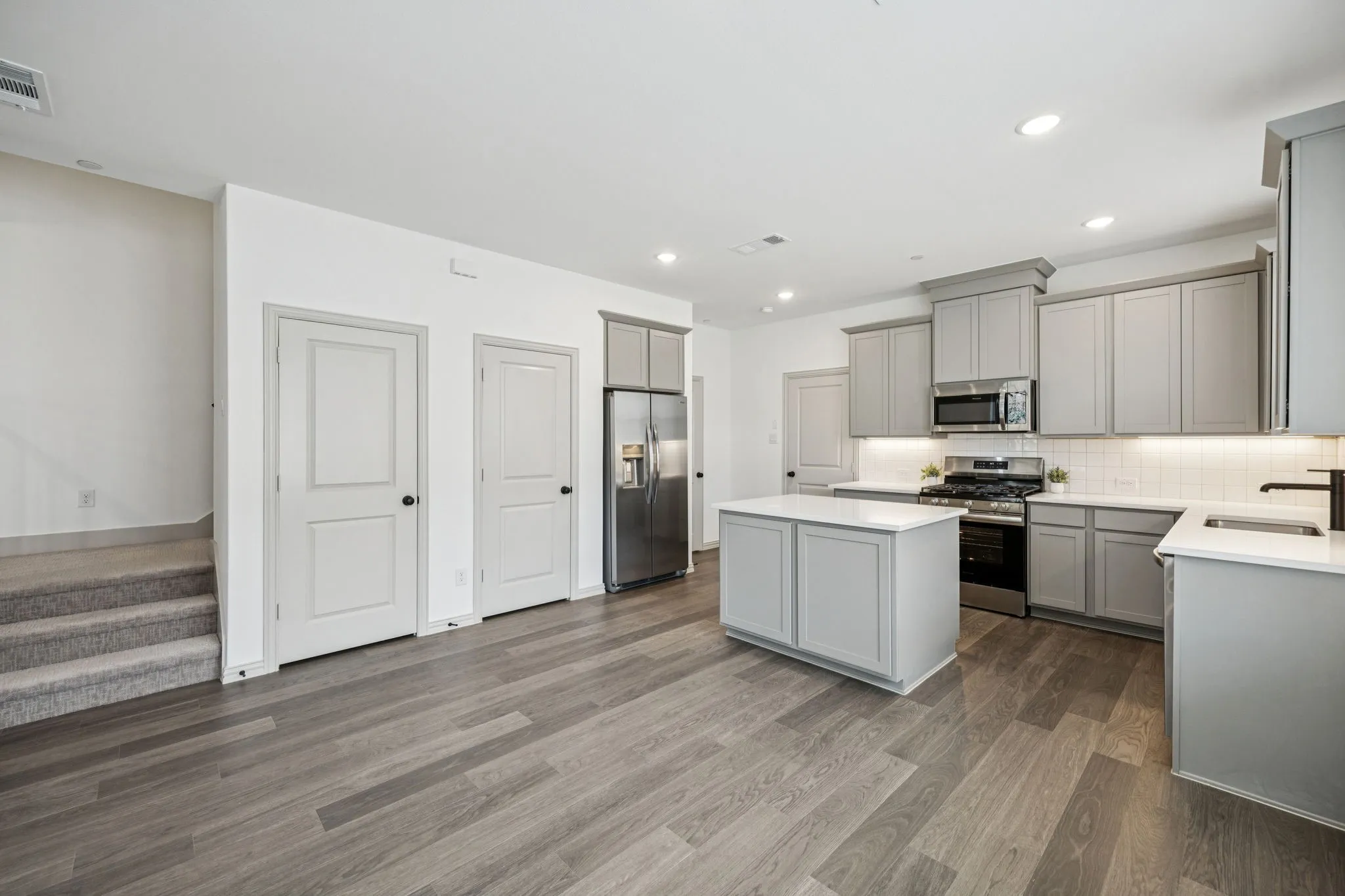 Open-concept kitchen with light gray cabinetry, stainless steel appliances, and a central island