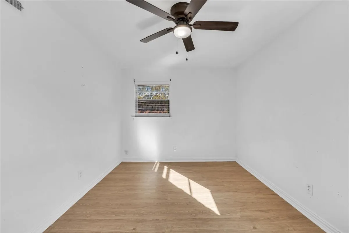 Wood-finish flooring, ceiling fan with integrated lighting, and window with blinds