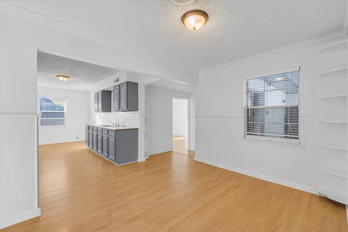 Wood-finish flooring, white walls with wainscoting, and built-in shelving