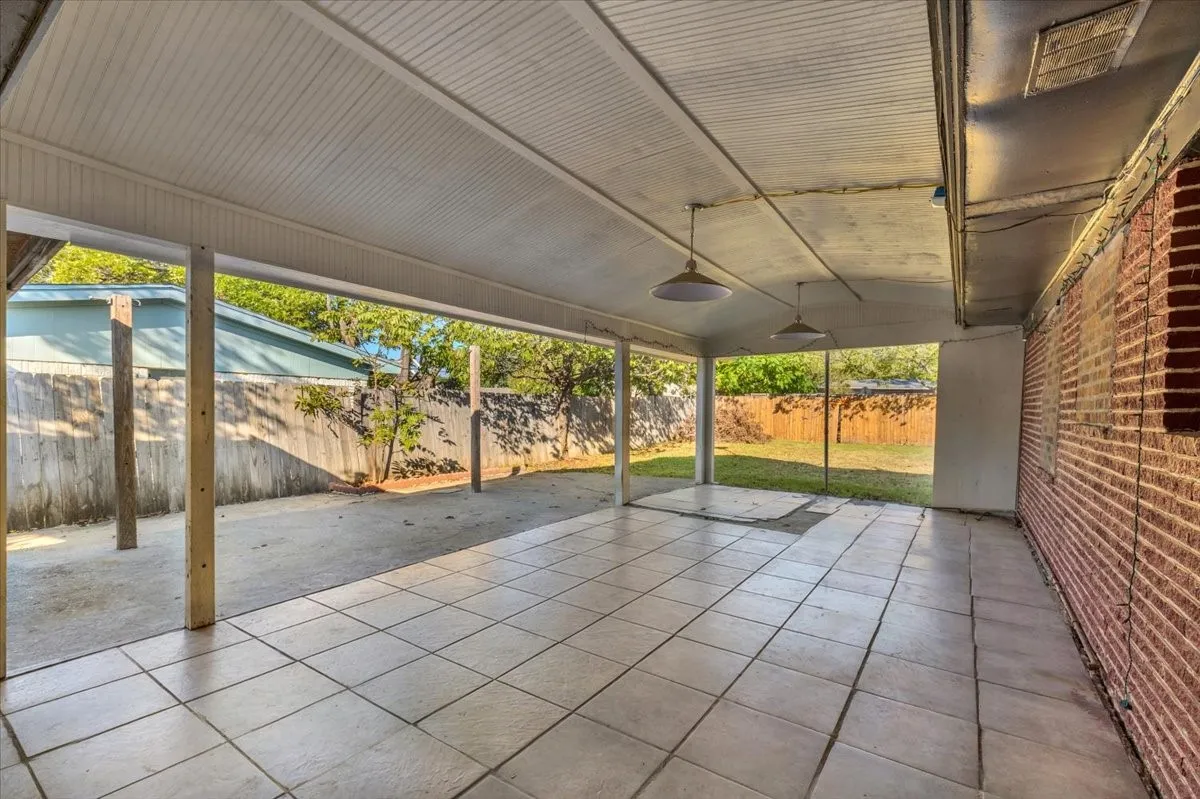 Covered patio with durable tile flooring and exposed brick wall