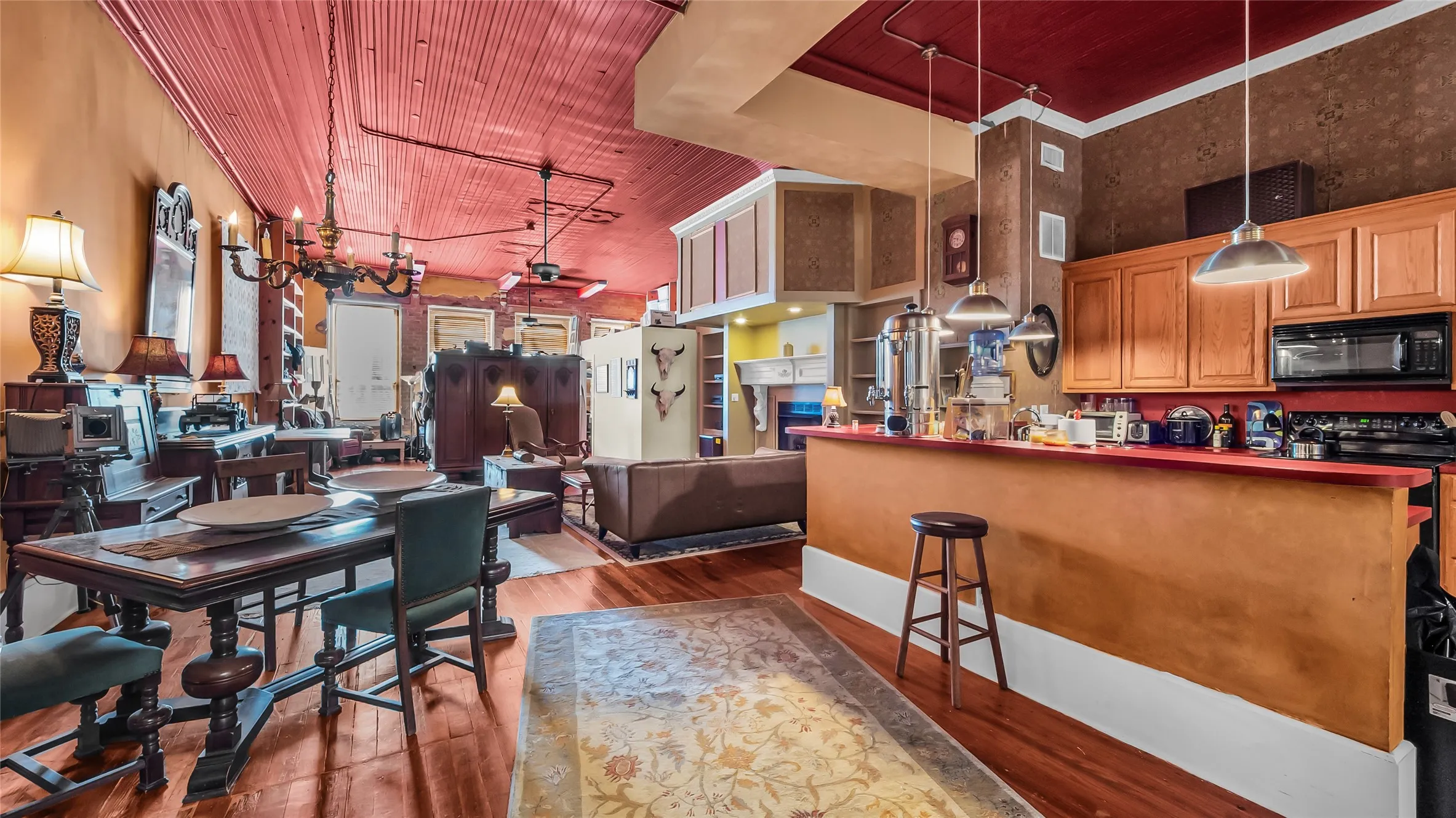 Hardwood flooring, wood-paneled ceiling, exposed conduit, recessed lighting, and a breakfast bar with pendant lighting