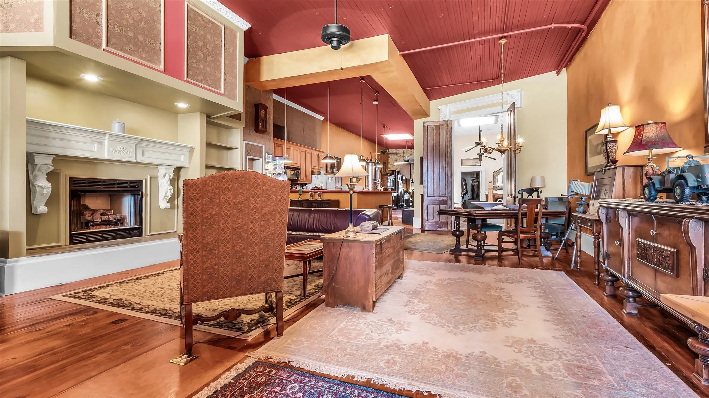 Living Area with Fireplace. Hardwood flooring, decorative fireplace, built-in shelving, high ceilings, and exposed ceiling beams