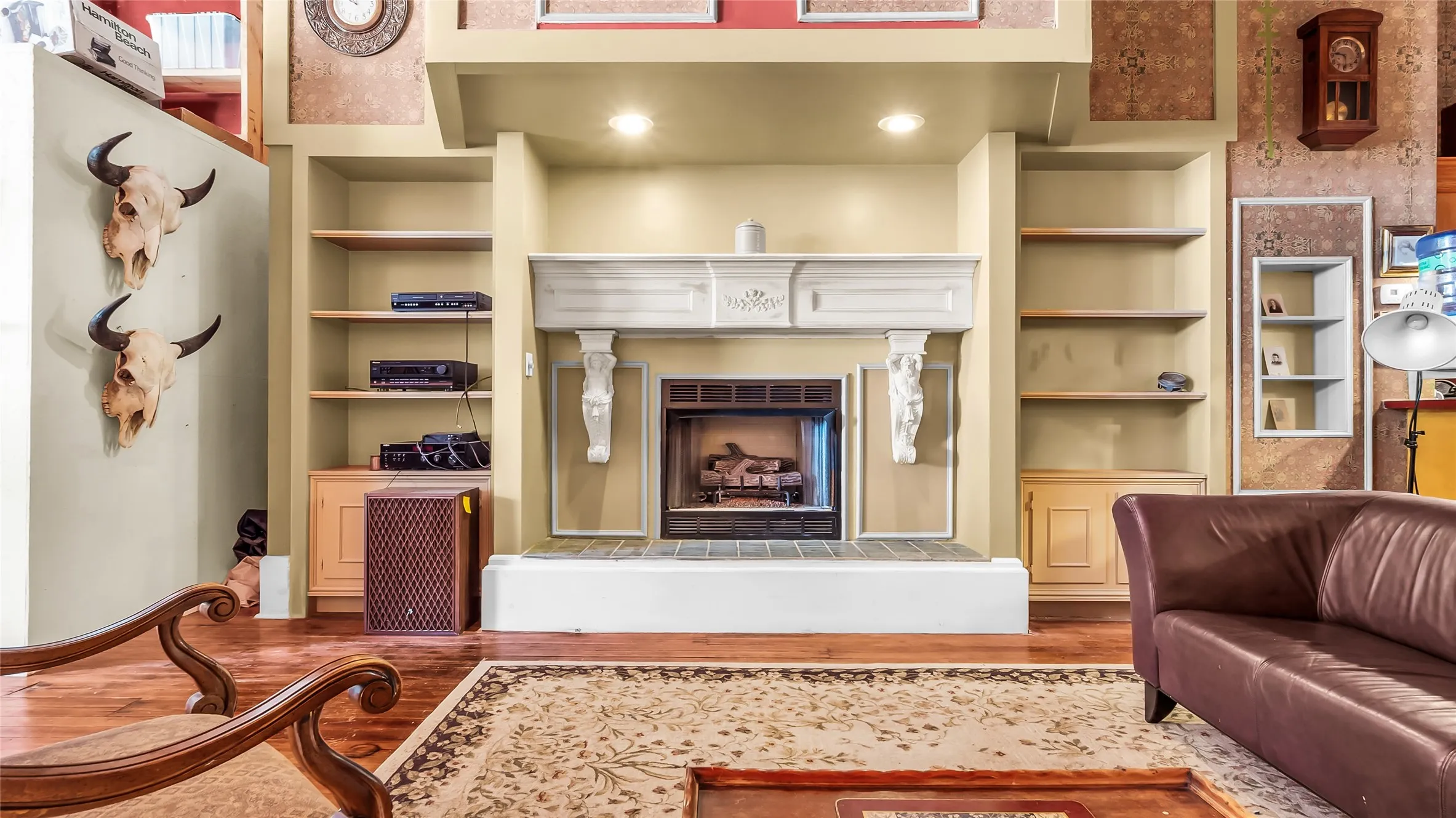 Elegant living room anchored by a custom built-in entertainment center featuring a fireplace with decorative surround, dual shelving units with display space, and recessed lighting