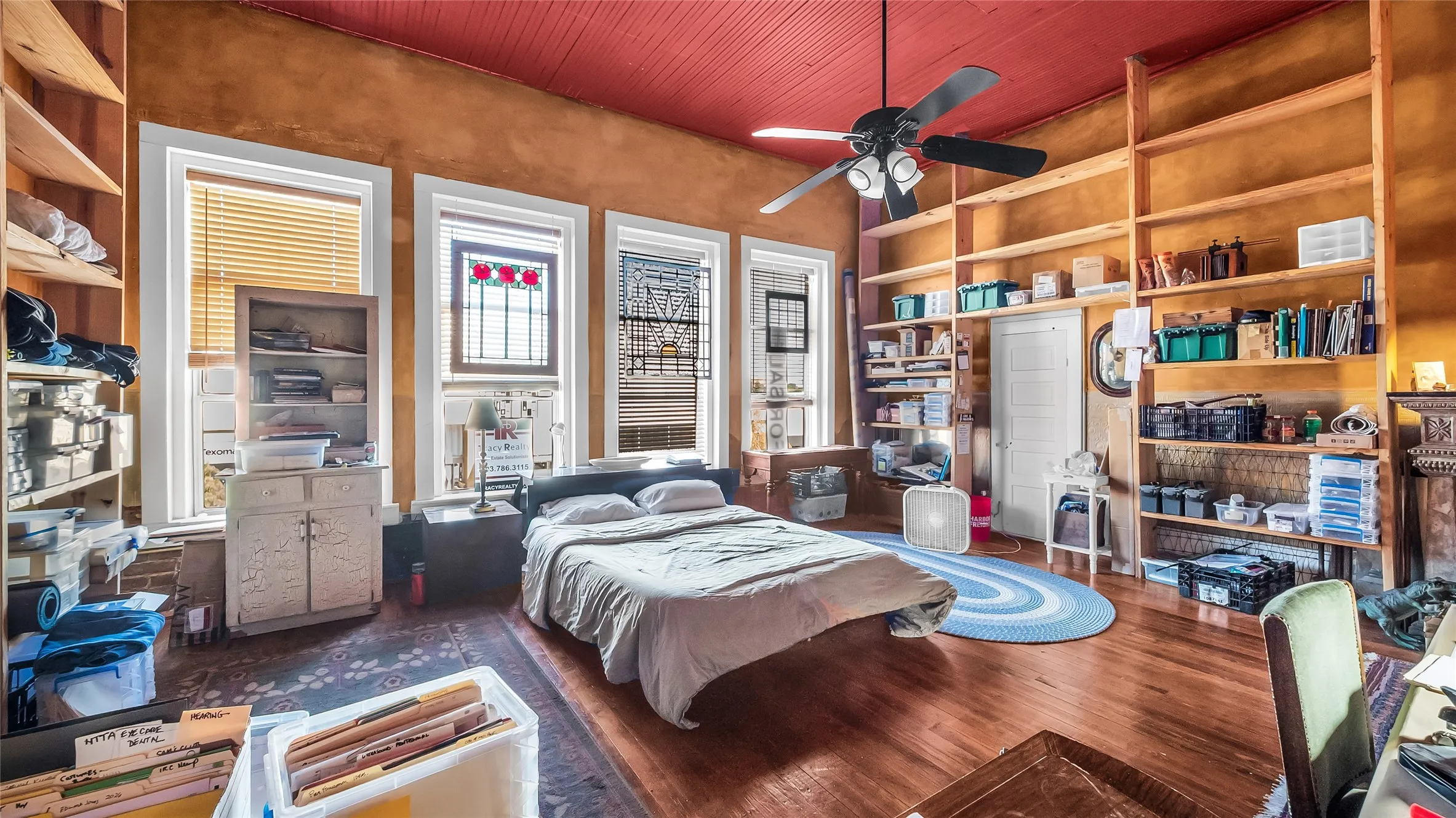 Hardwood flooring, painted wood ceiling, multiple windows with decorative stained glass, built-in shelving, and ceiling fan with lighting