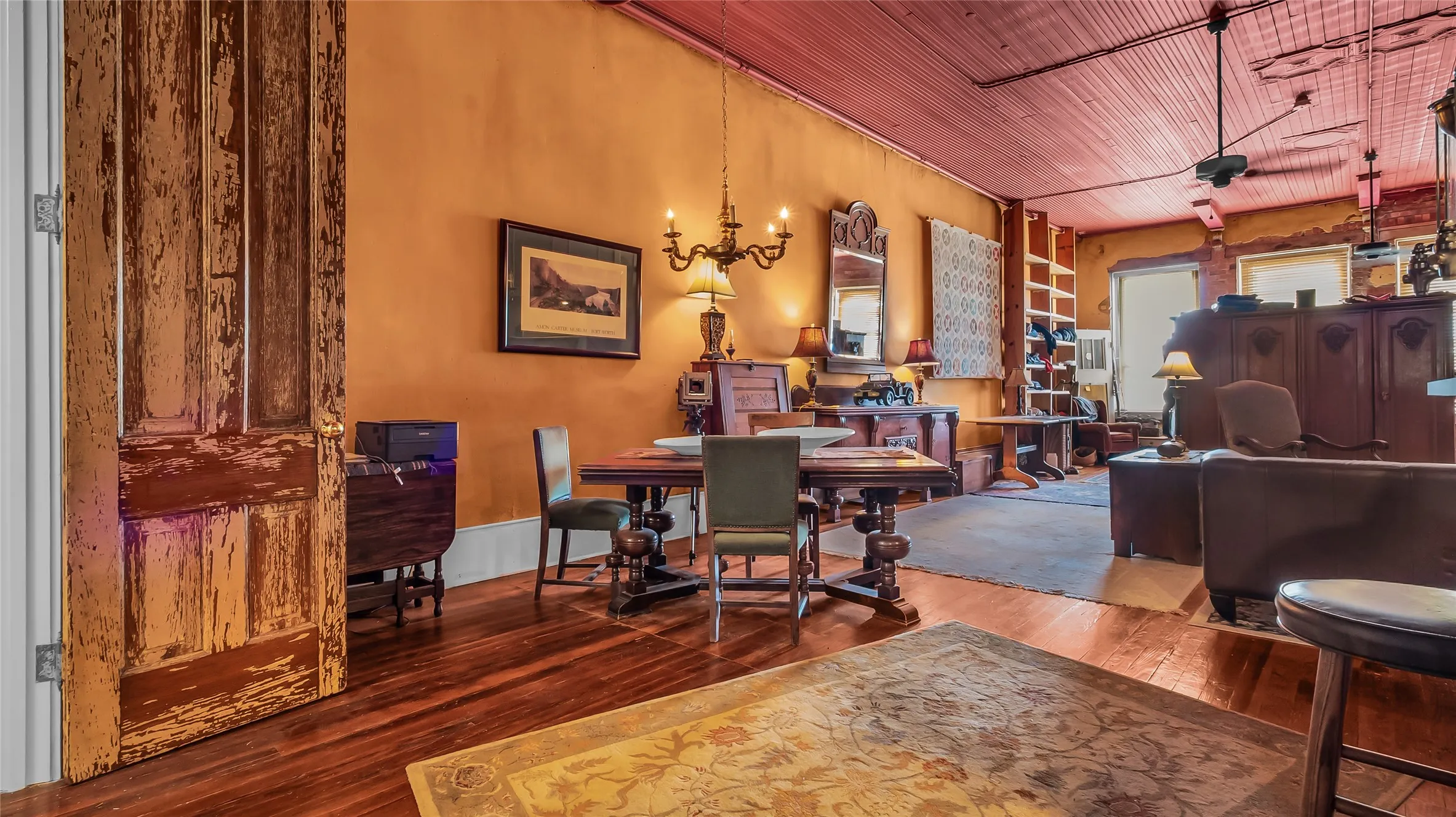 Hardwood flooring, painted wood ceiling, exposed brick accents, built-in shelving, and a chandelier lighting fixture
