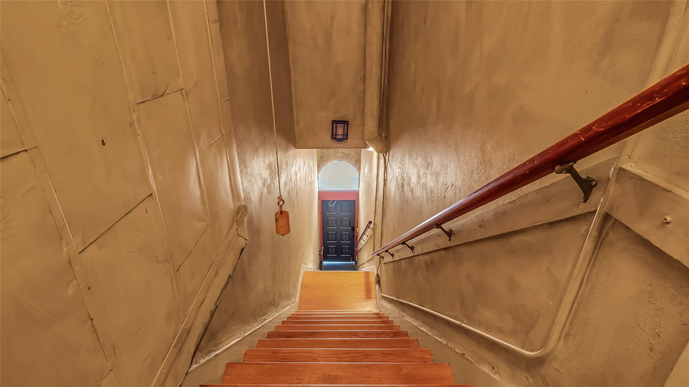 LOFT staircase. Hardwood staircase with a dark wood handrail, textured wall finish, and overhead lighting