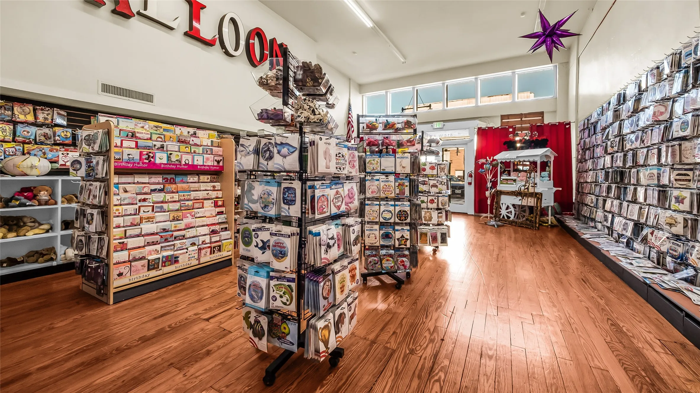 Hardwood flooring with a warm finish, high ceilings, perimeter display shelving, and transom windows