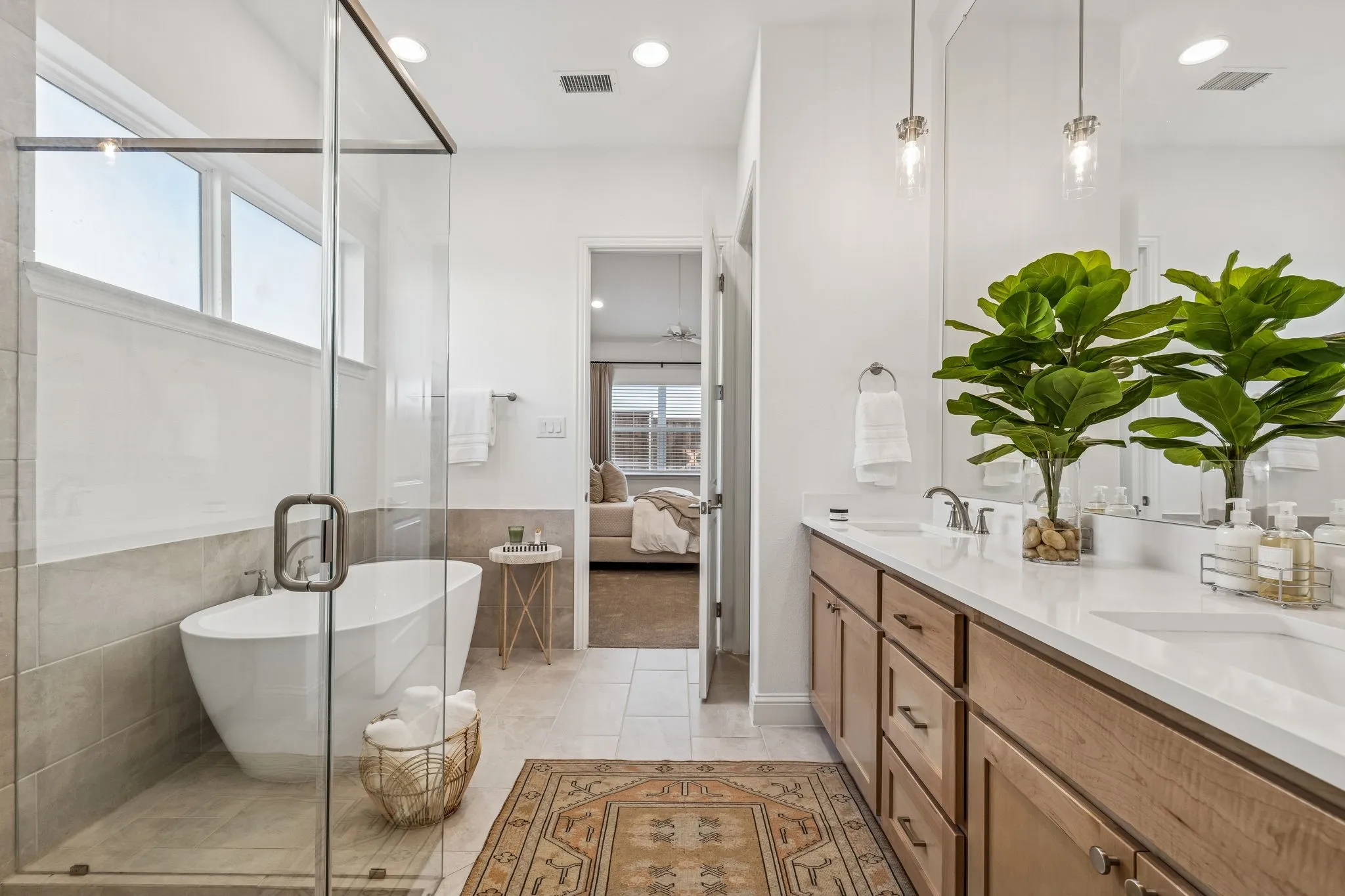 Freestanding soaking tub, glass-enclosed shower, dual vanity with undermount sinks, and wood-finish cabinetry