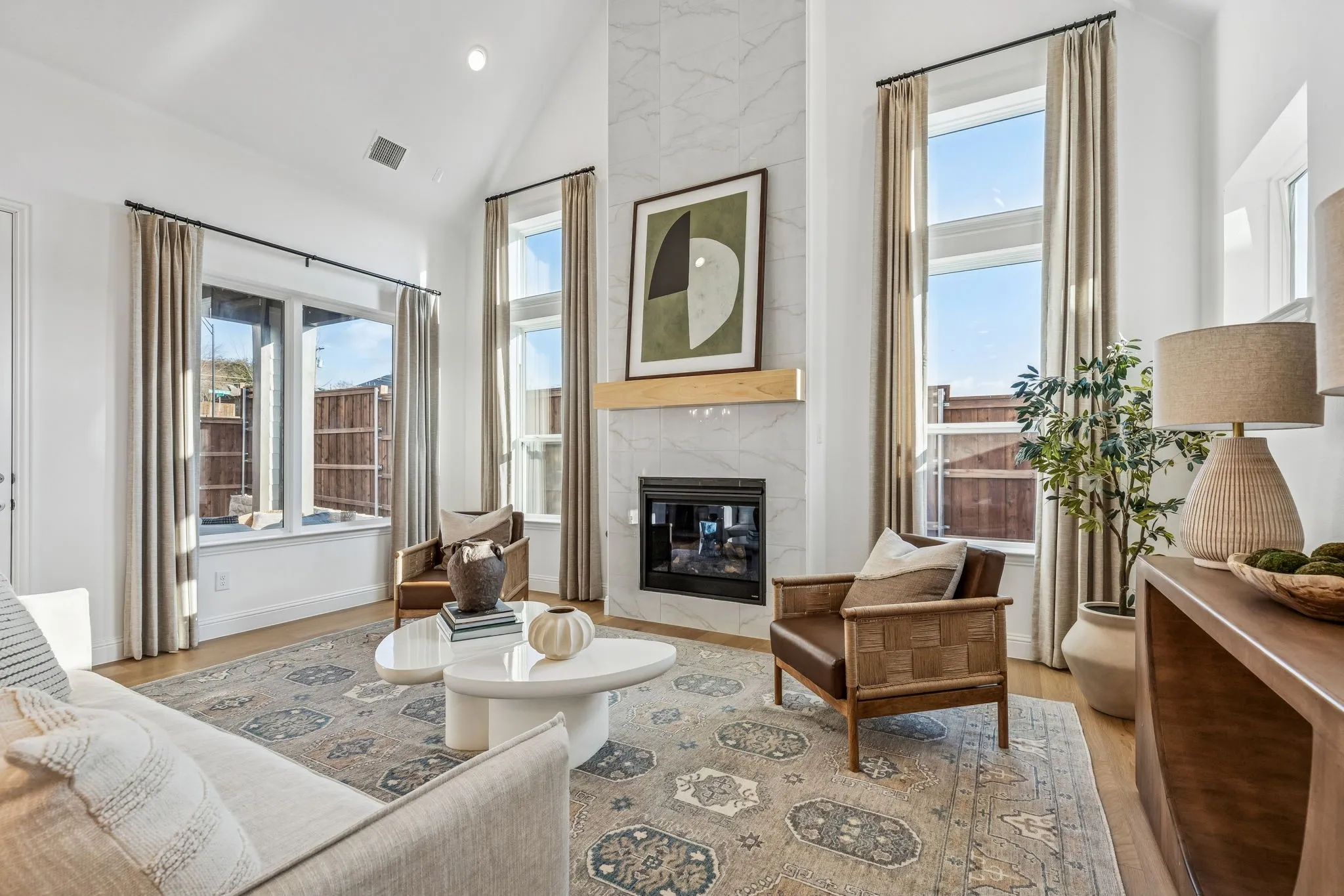 Vaulted ceiling with recessed lighting, large windows, wood-finish flooring, tiled fireplace with a wood mantle, and a built-in fireplace insert