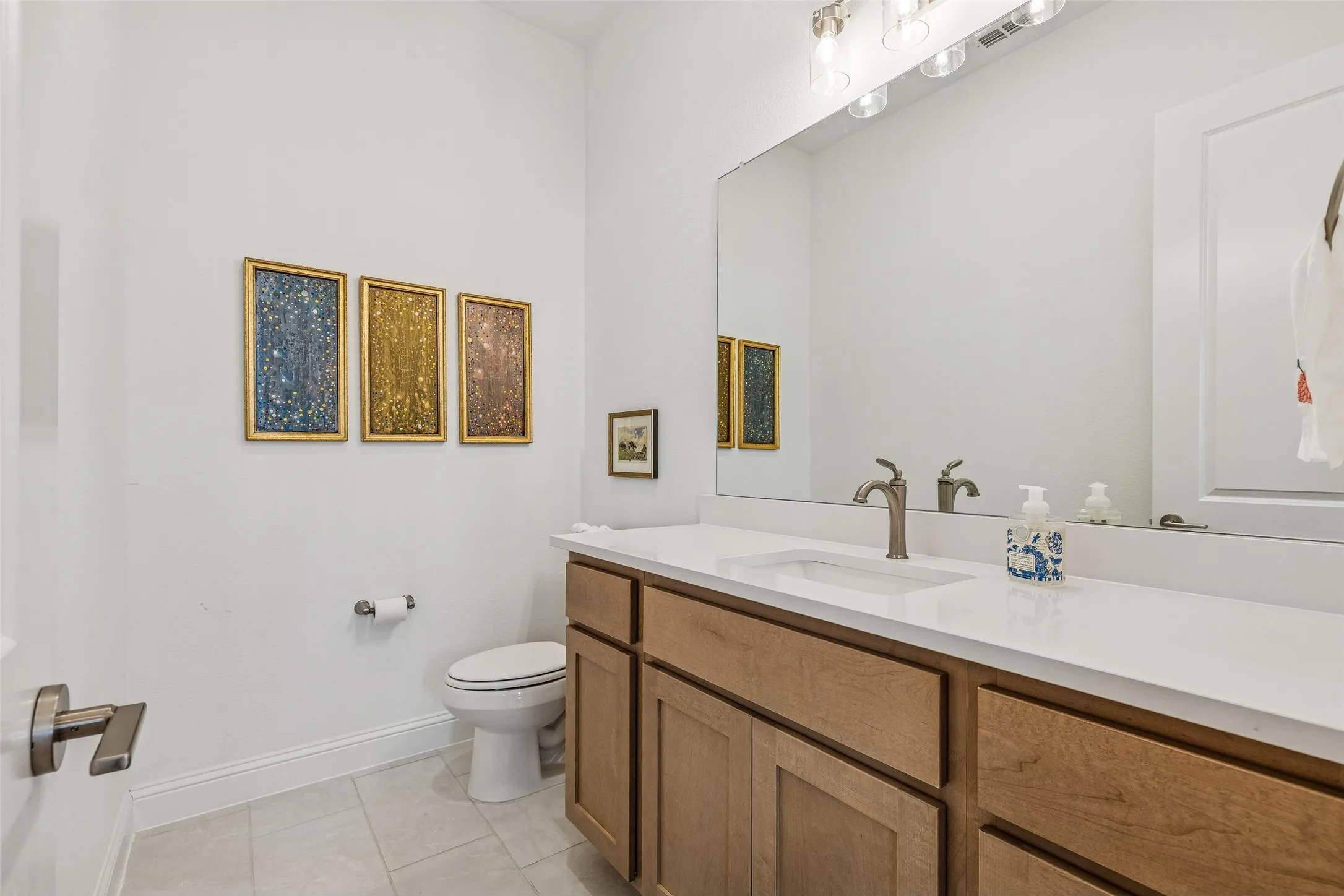Vanity with wood-finish cabinetry, integrated rectangular sink, and white countertop