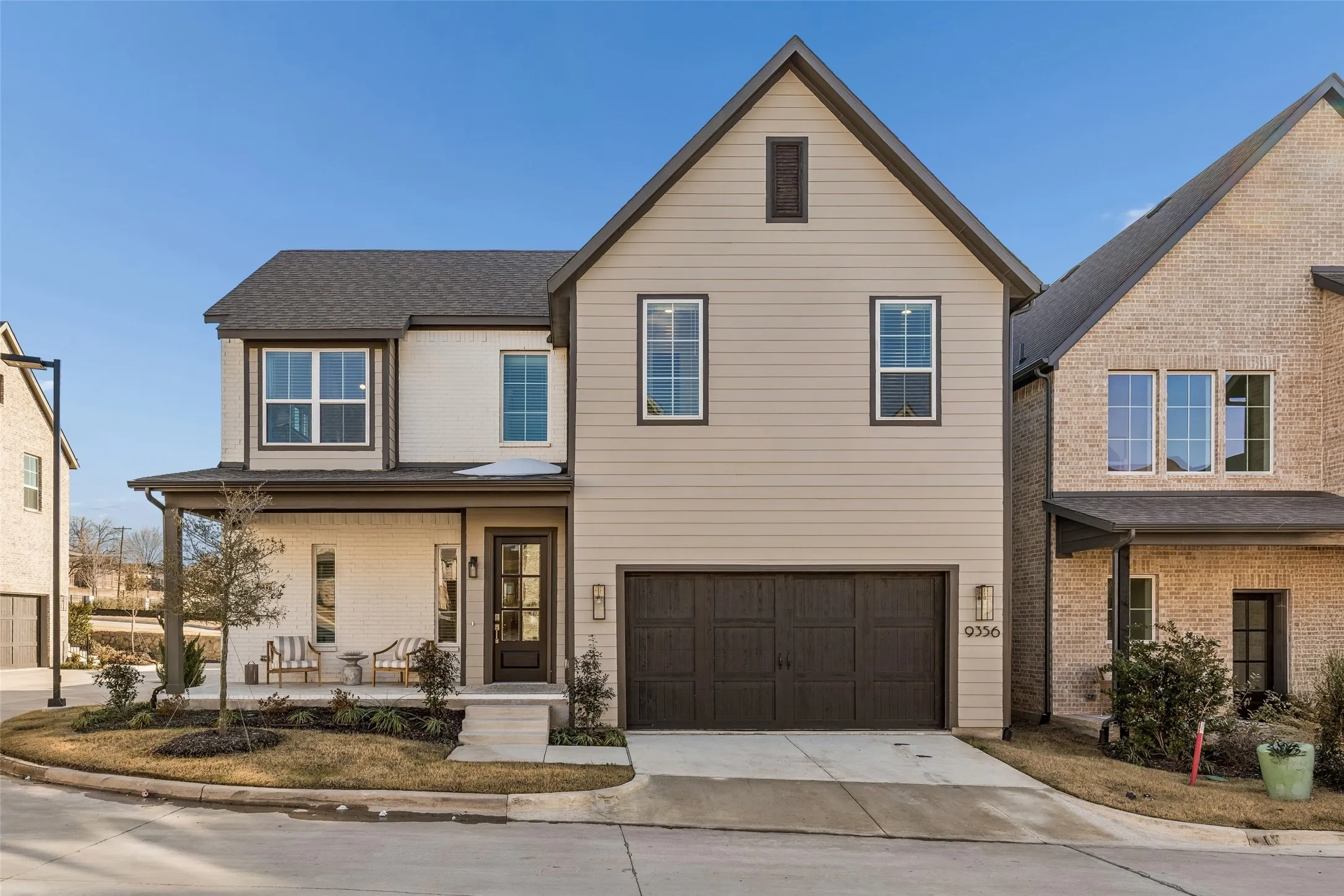 Contemporary exterior featuring a covered front porch, a two-car garage, and a combination of brick and horizontal siding
