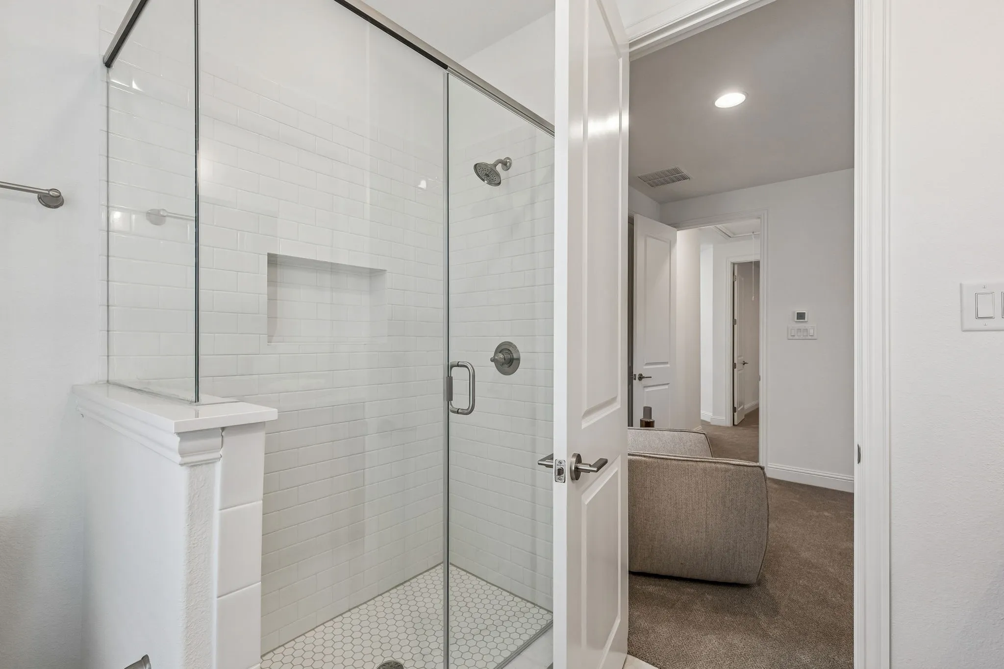 Glass-enclosed shower with subway tile surround, integrated shower niche, and hexagonal tile flooring