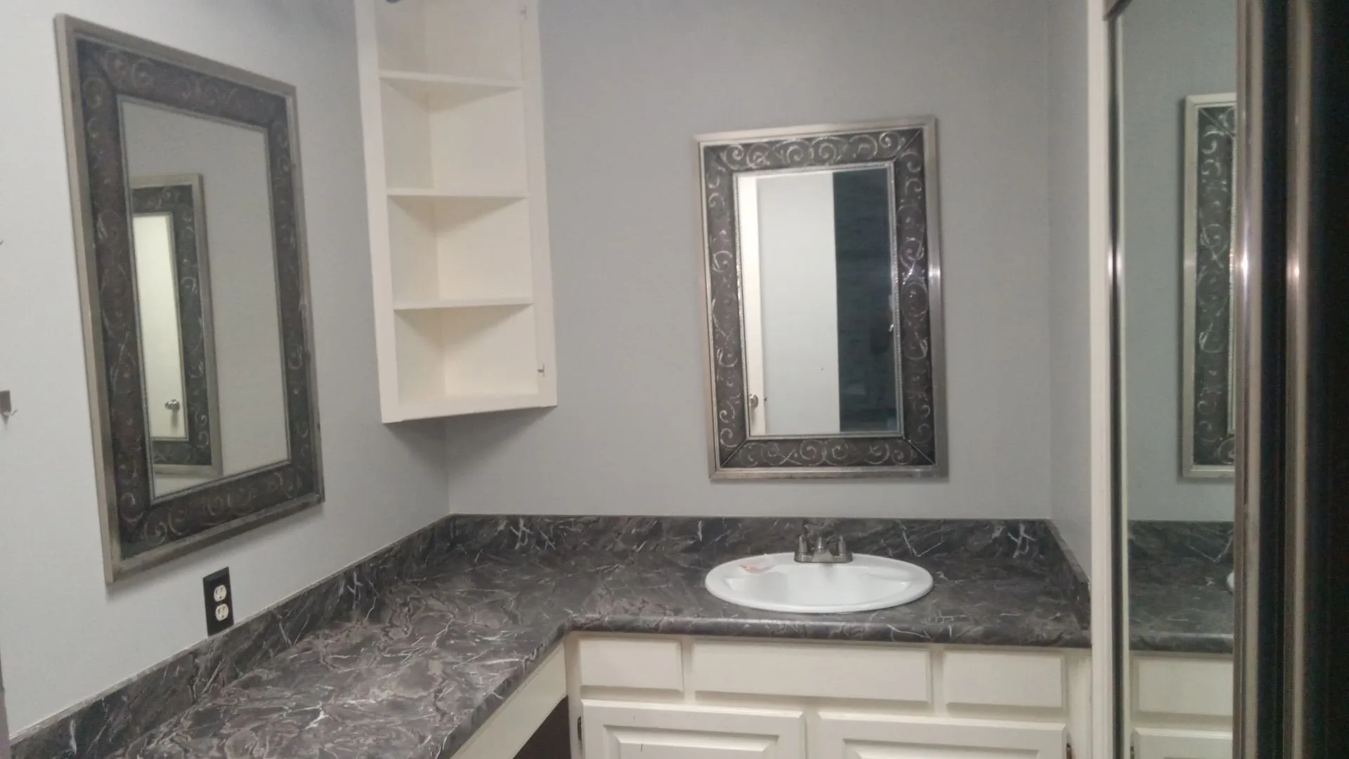Vanity with integrated sink, patterned countertop, and decorative framed mirror