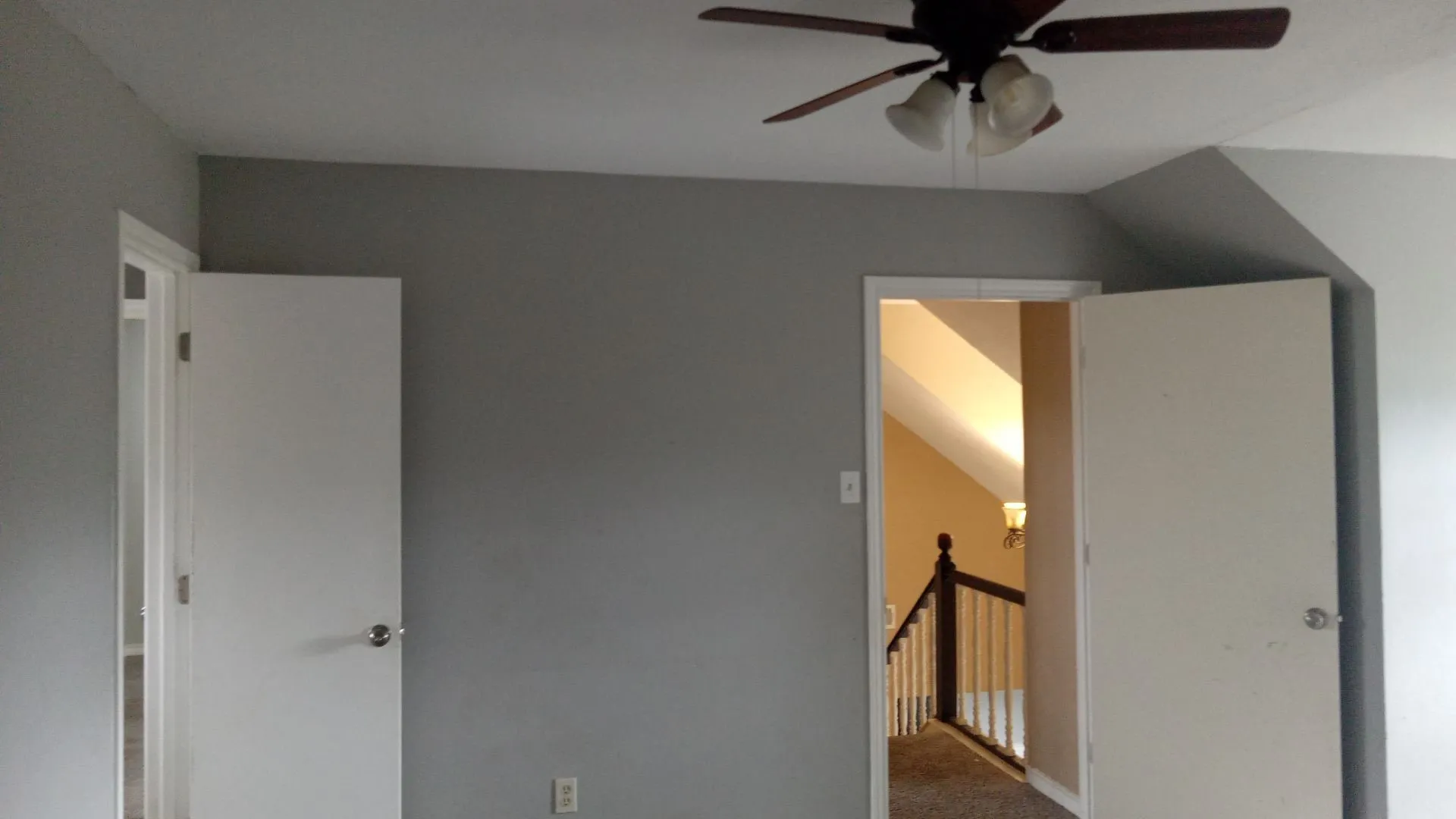 Ceiling fan with light fixture, gray painted walls, white trim, white interior doors, and carpeted flooring