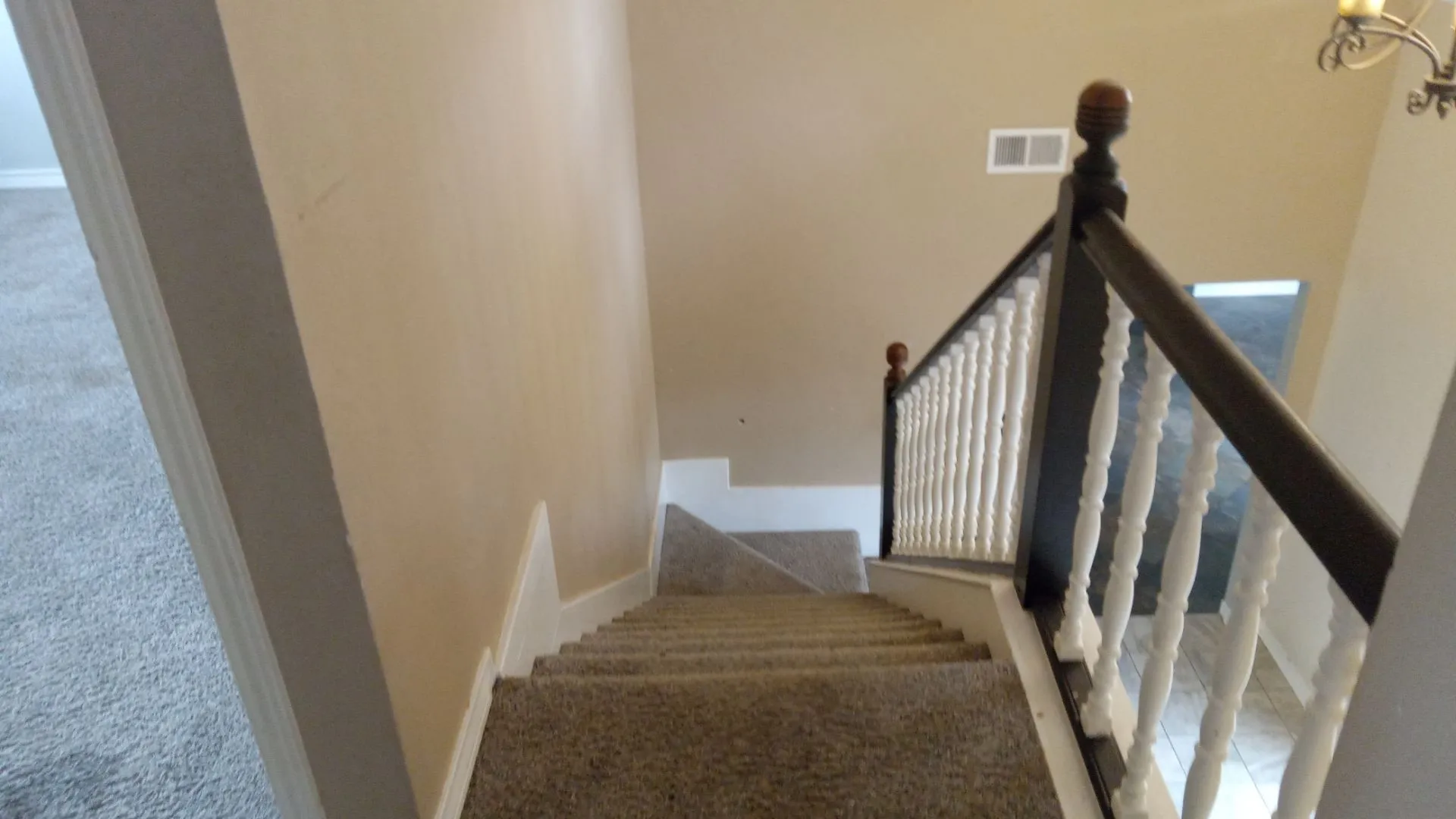 Carpeted staircase featuring a dark-stained wood handrail and white balusters