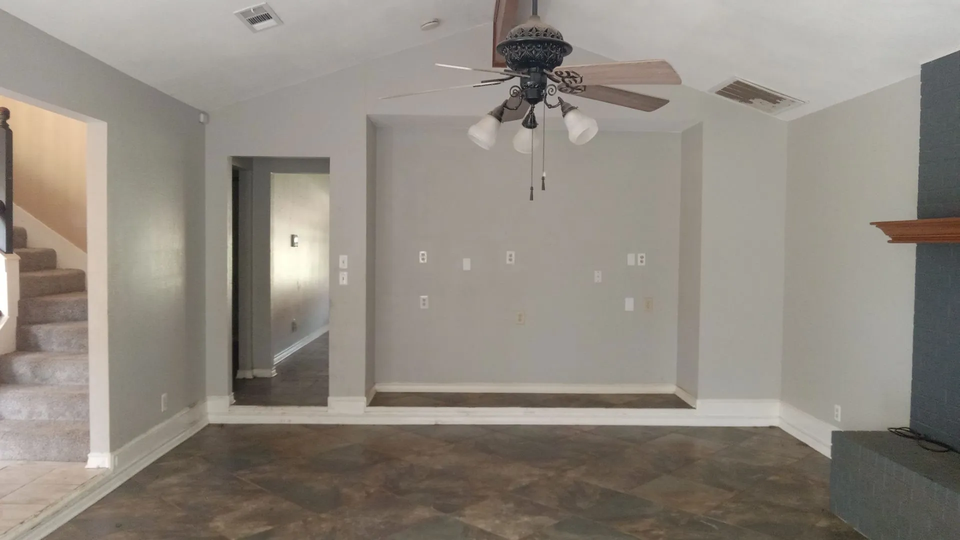 Vaulted ceiling with a ceiling fan light fixture, integrated media niche, stone-finish flooring, and a built-in fireplace