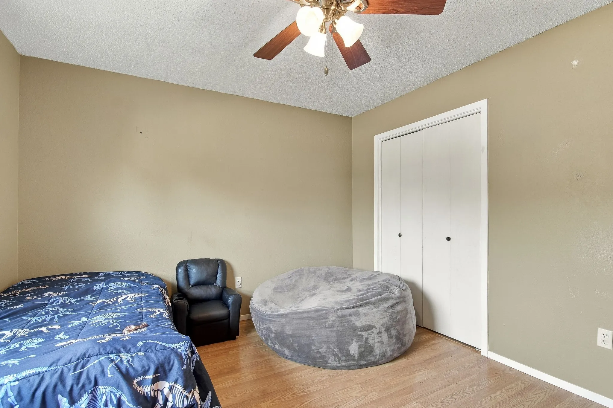 Wood-finish flooring, ceiling fan with integrated lighting, and a closet with bi-fold doors