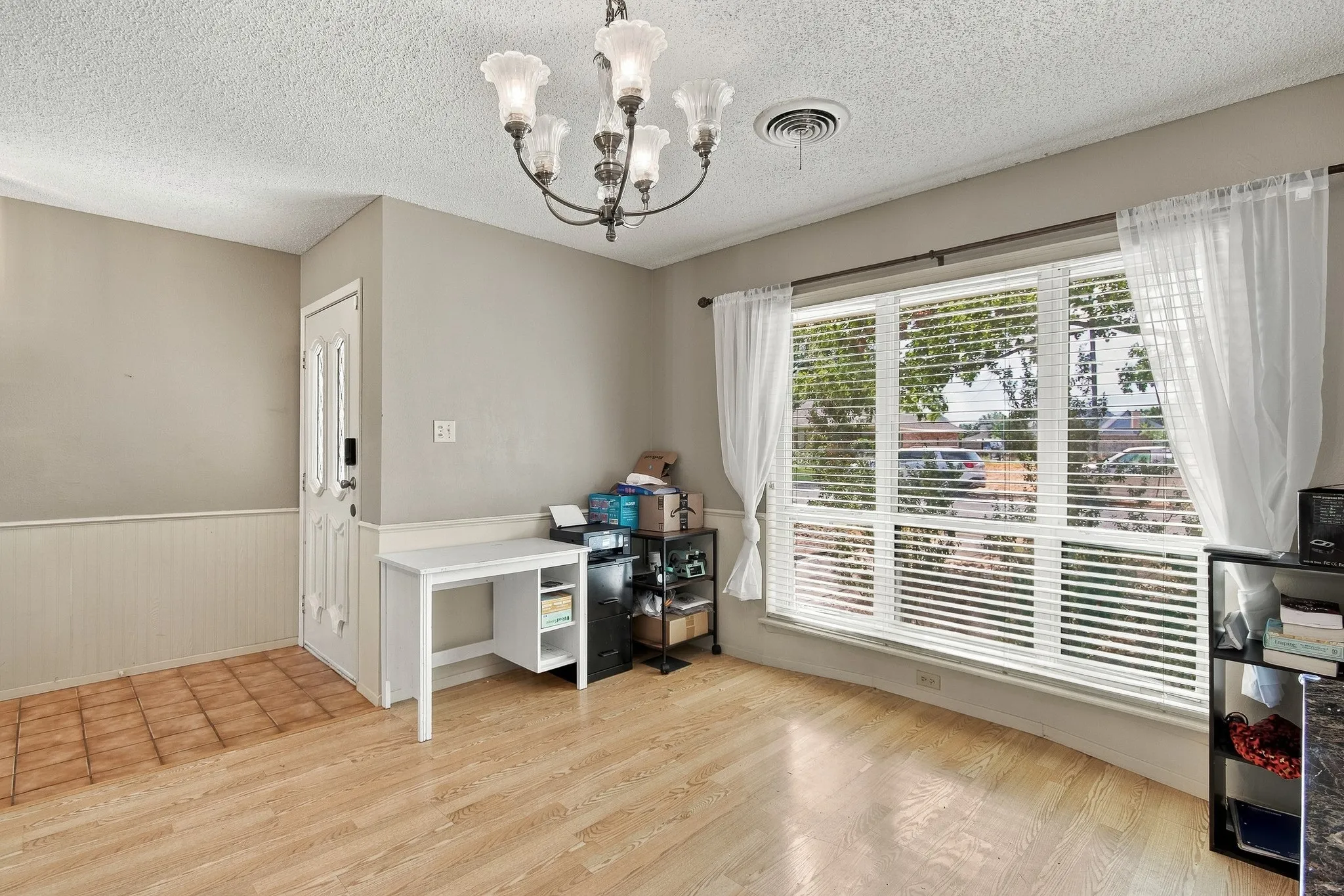 Wood-finish flooring, light gray wall paint, and a multi-pane window with white blinds and sheer curtains