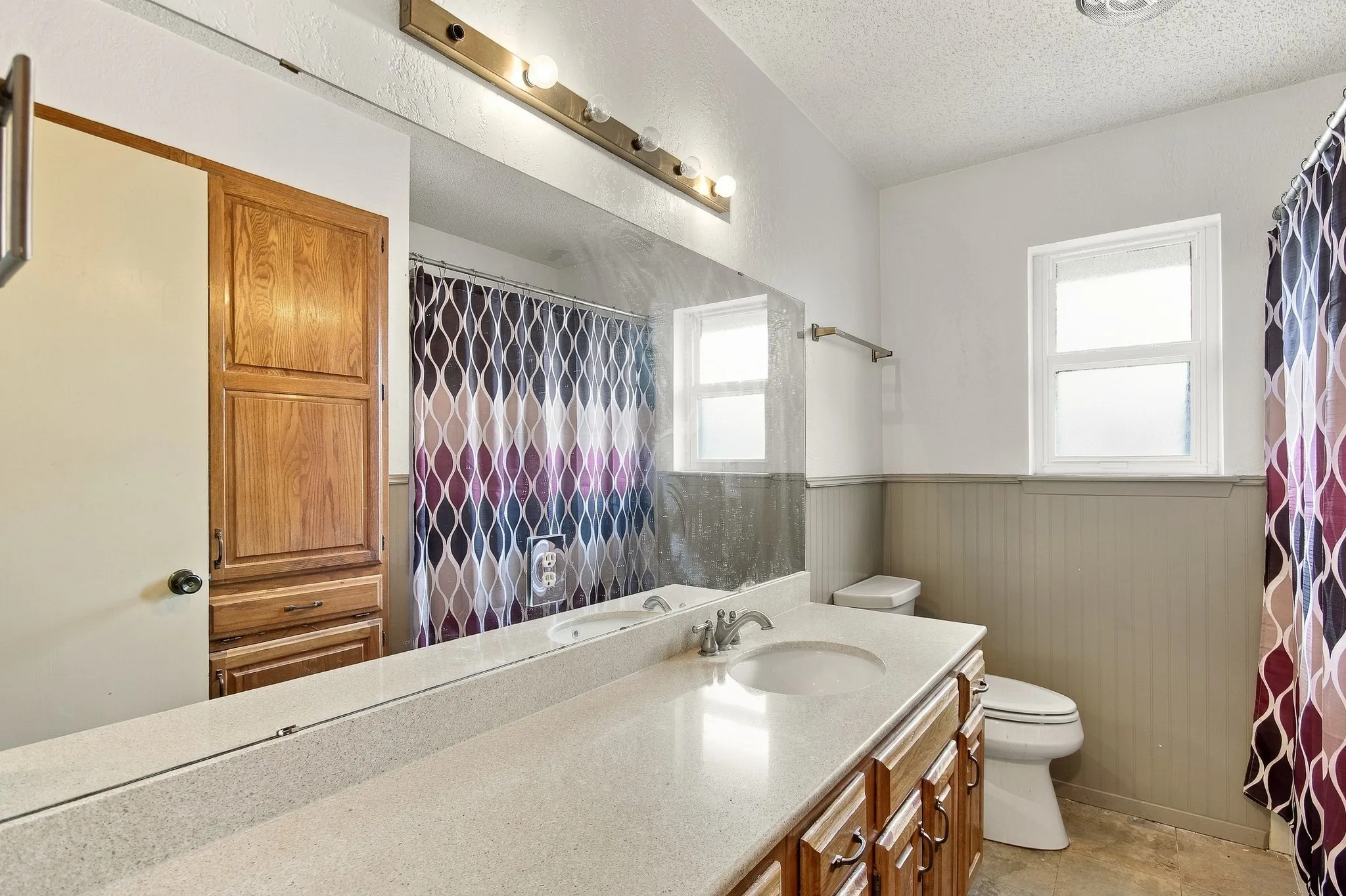 Integrated vanity with a single basin sink, light-toned countertop, and wood-finish cabinetry