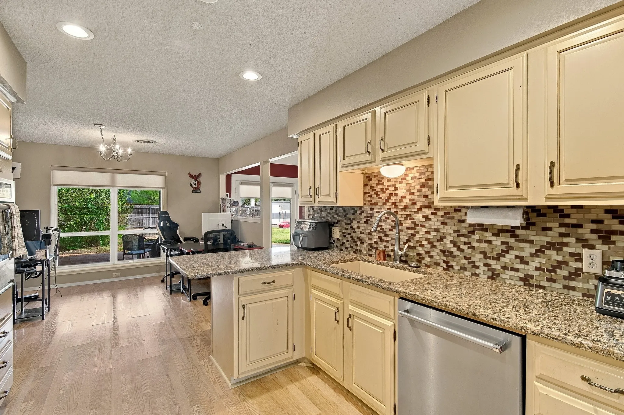 Kitchen with granite countertops, wood-finish flooring, undermount sink, mosaic tile backsplash, and recessed lighting
