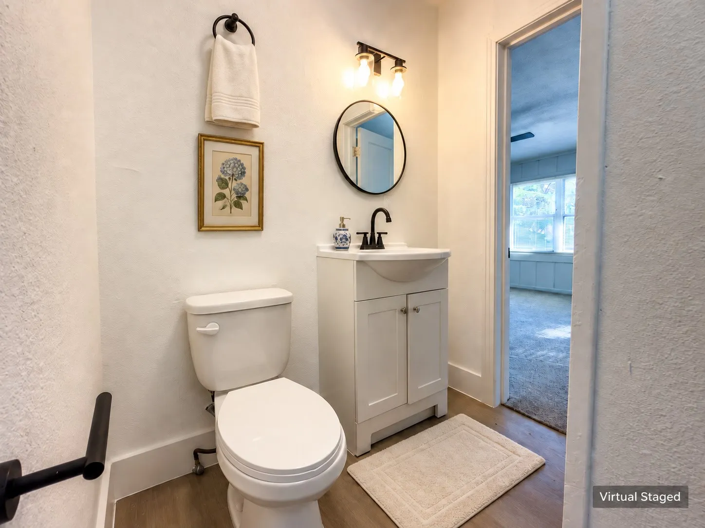 White vanity with cabinet storage, matte black faucet, and coordinating round mirror