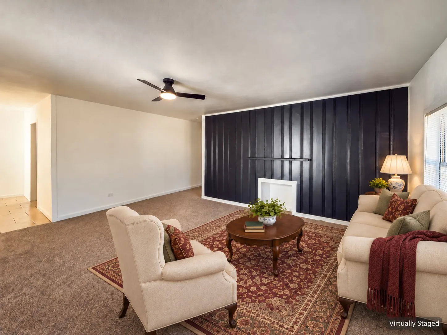 Recessed wall feature with dark paneling, overhead ceiling fan, and light-toned carpeting