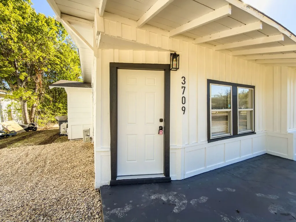 Vertical board and batten siding, black trimmed windows, black entry door, black exterior lighting, and a black painted porch