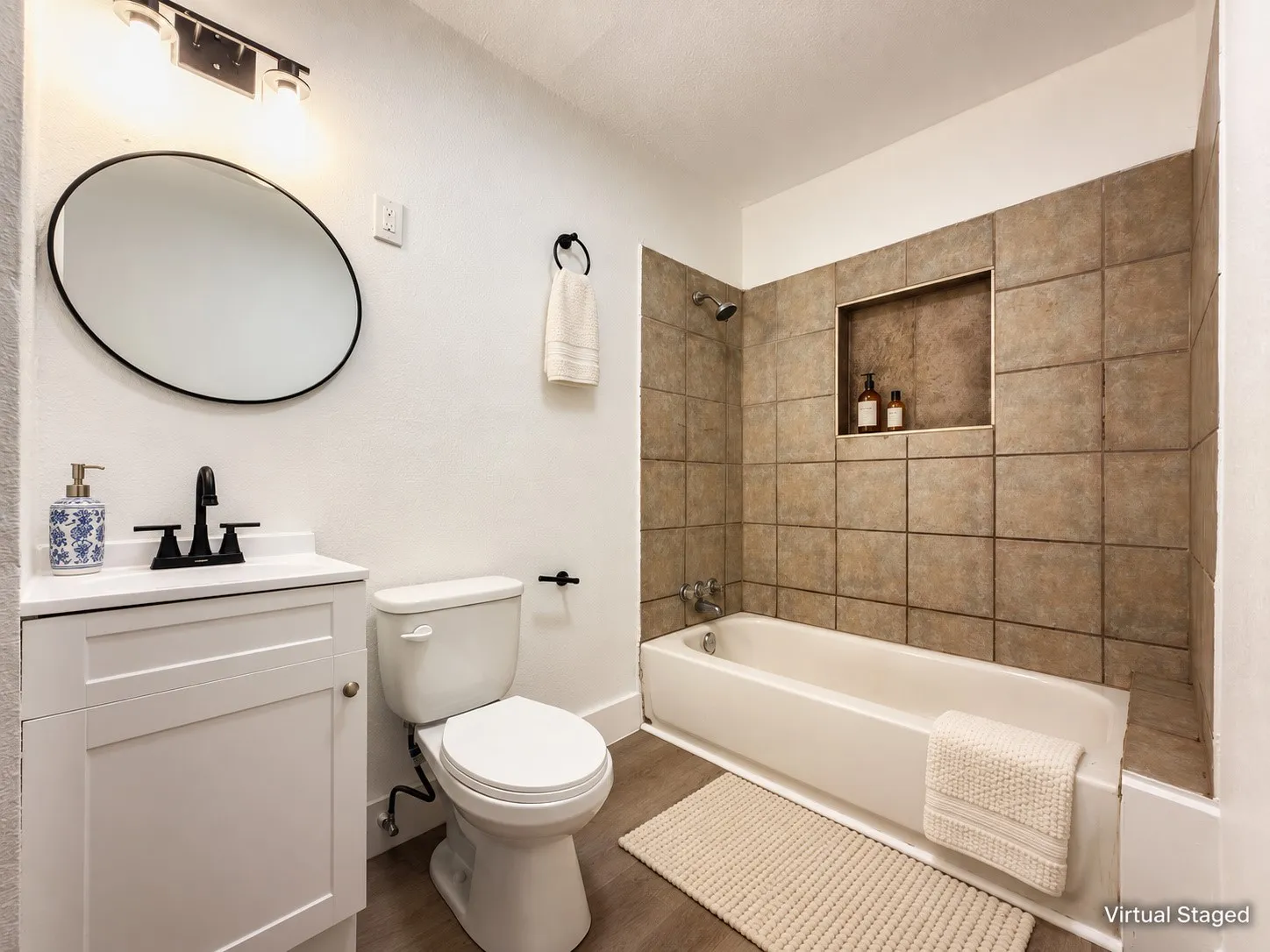White vanity with a single basin sink, matte black faucet, and an oval mirror