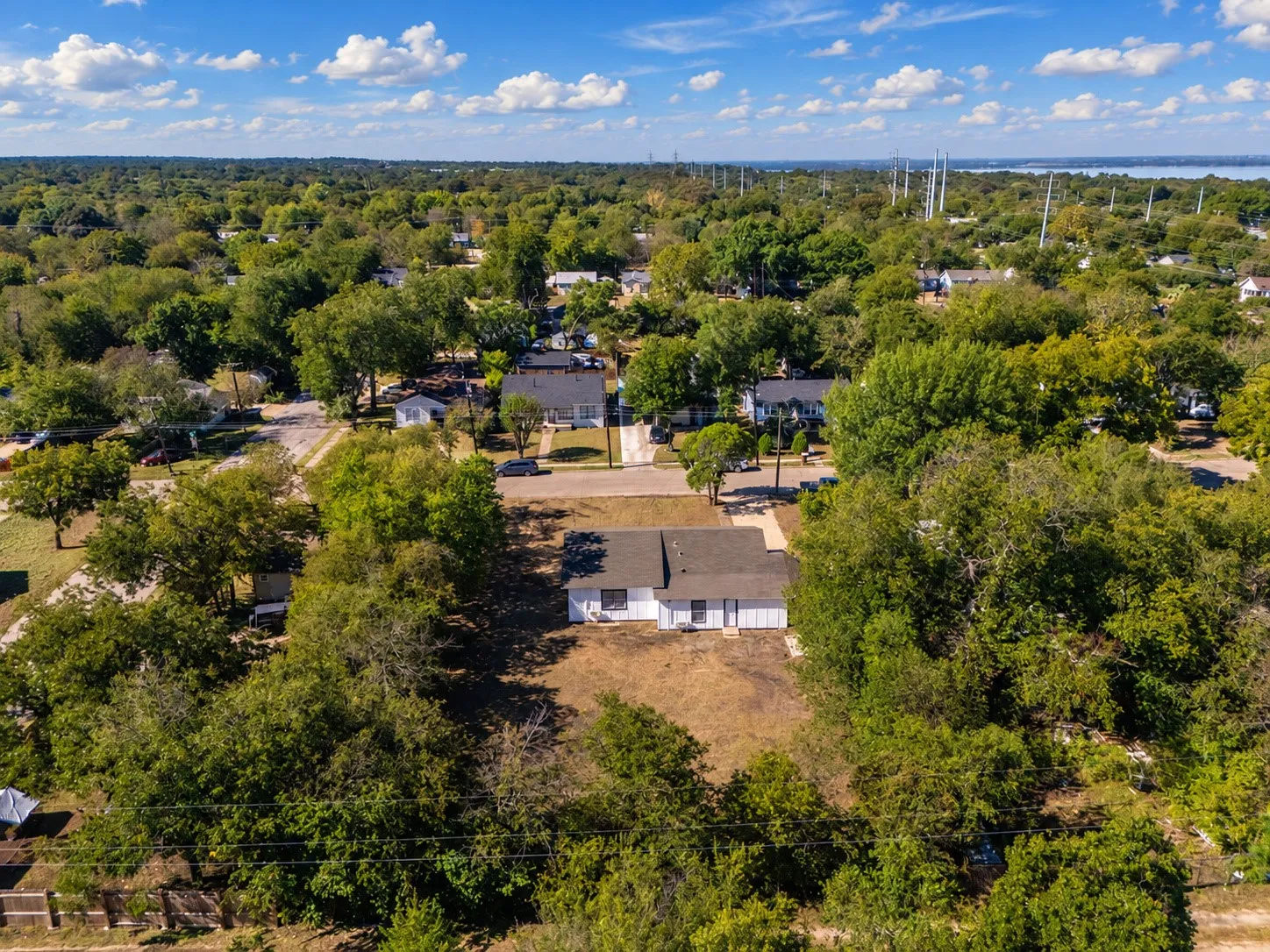 Aerial perspective showcasing a residential lot with mature trees, surrounded by established neighborhood homes