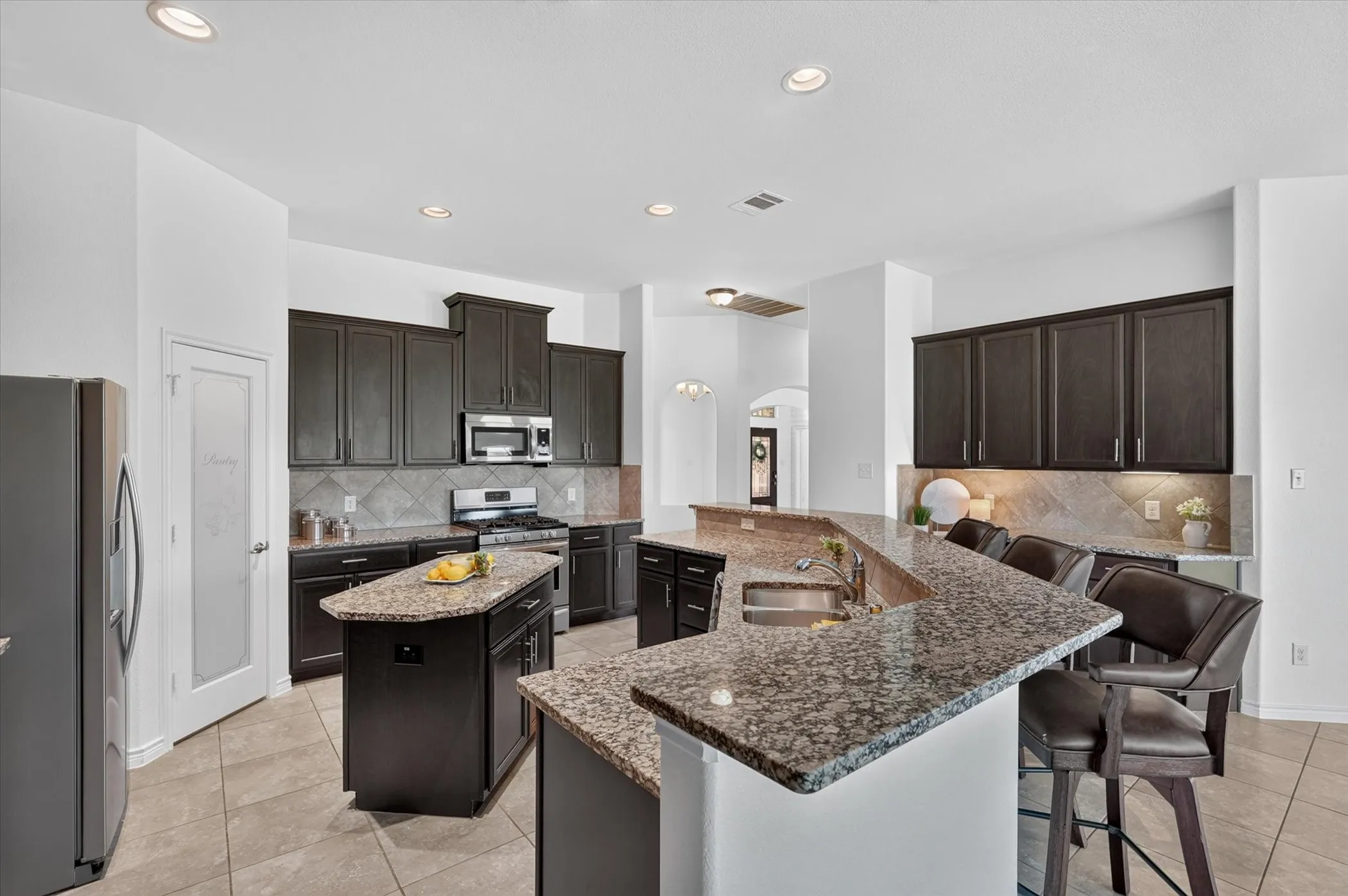 Kitchen featuring dark wood-finish cabinetry, granite countertops, stainless steel appliances, and a central island