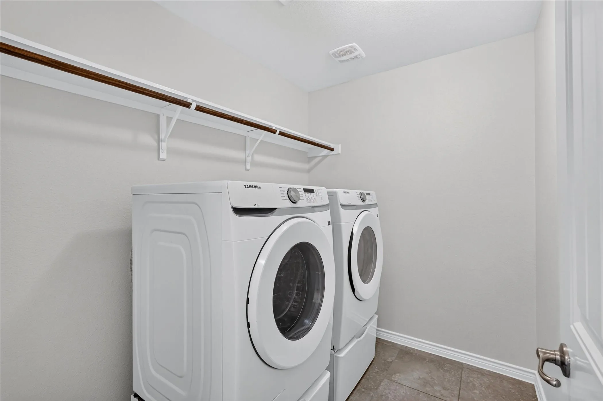 Laundry area featuring a hanging rod, wall-mounted brackets, and tile flooring